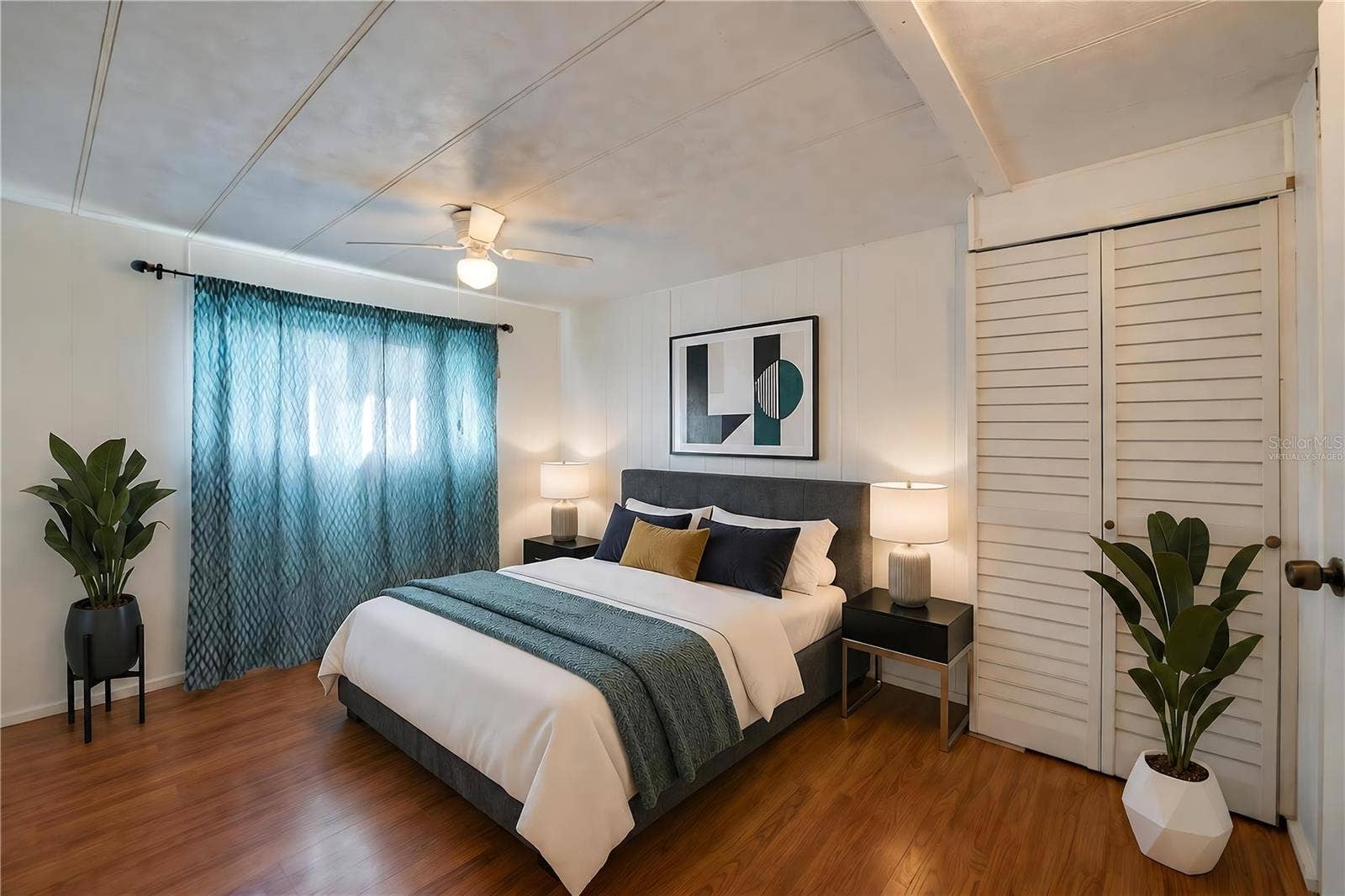 Virtually Staged - Bright, versatile bedroom with paneled walls, a ceiling fan with light, a large window for natural light, and a louvered-door closet.