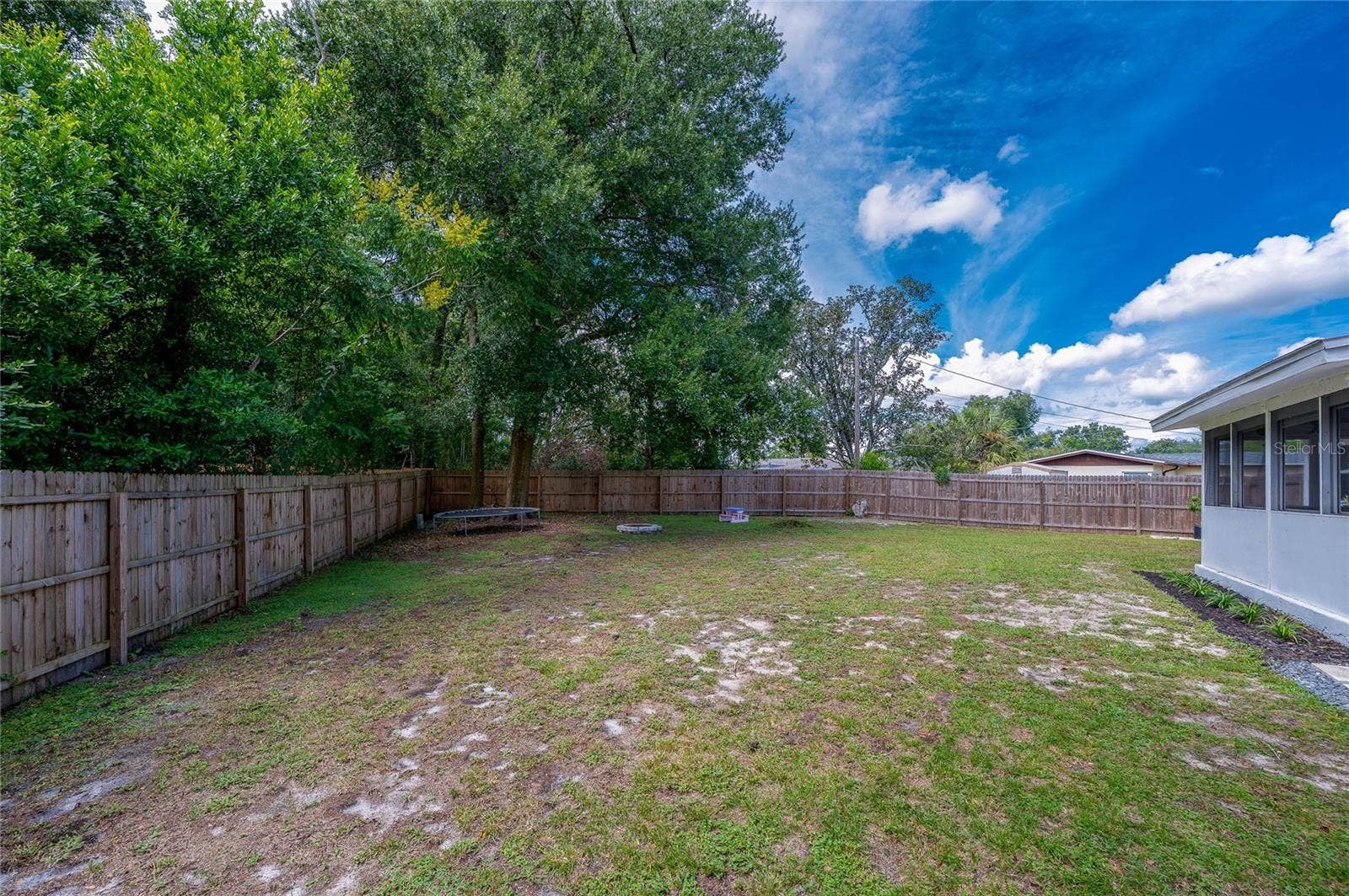 605 E NORMANDY BOULEVARD, Deltona, FL 32725 Spacious backyard enclosed by a full wooden privacy fence and lined with mature trees along the perimeter.
