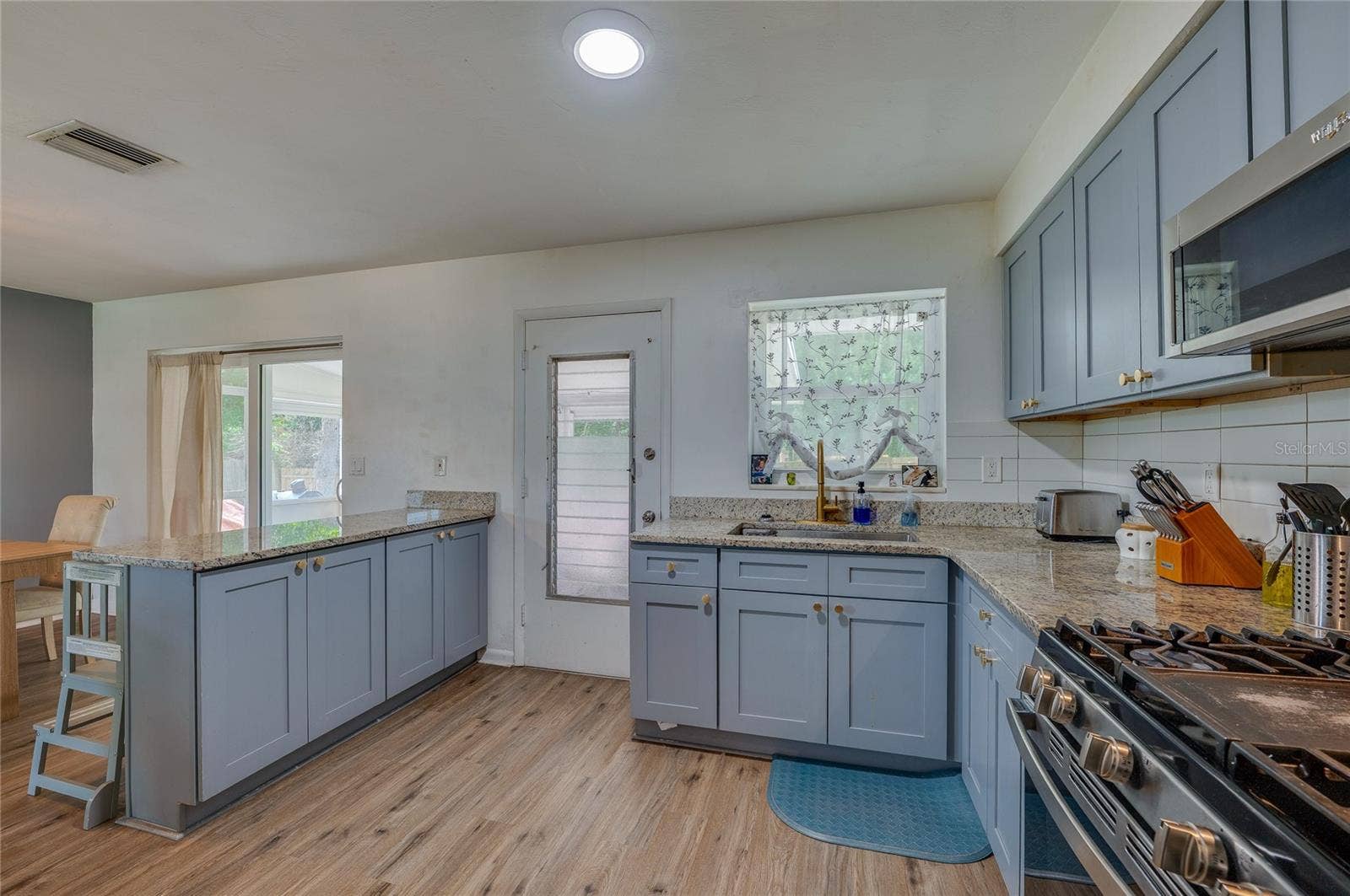 605 E NORMANDY BOULEVARD, Deltona, FL 32725 Well-appointed kitchen setup complete with an electric range stove, stainless steel appliances, granite counters, and direct outdoor access.