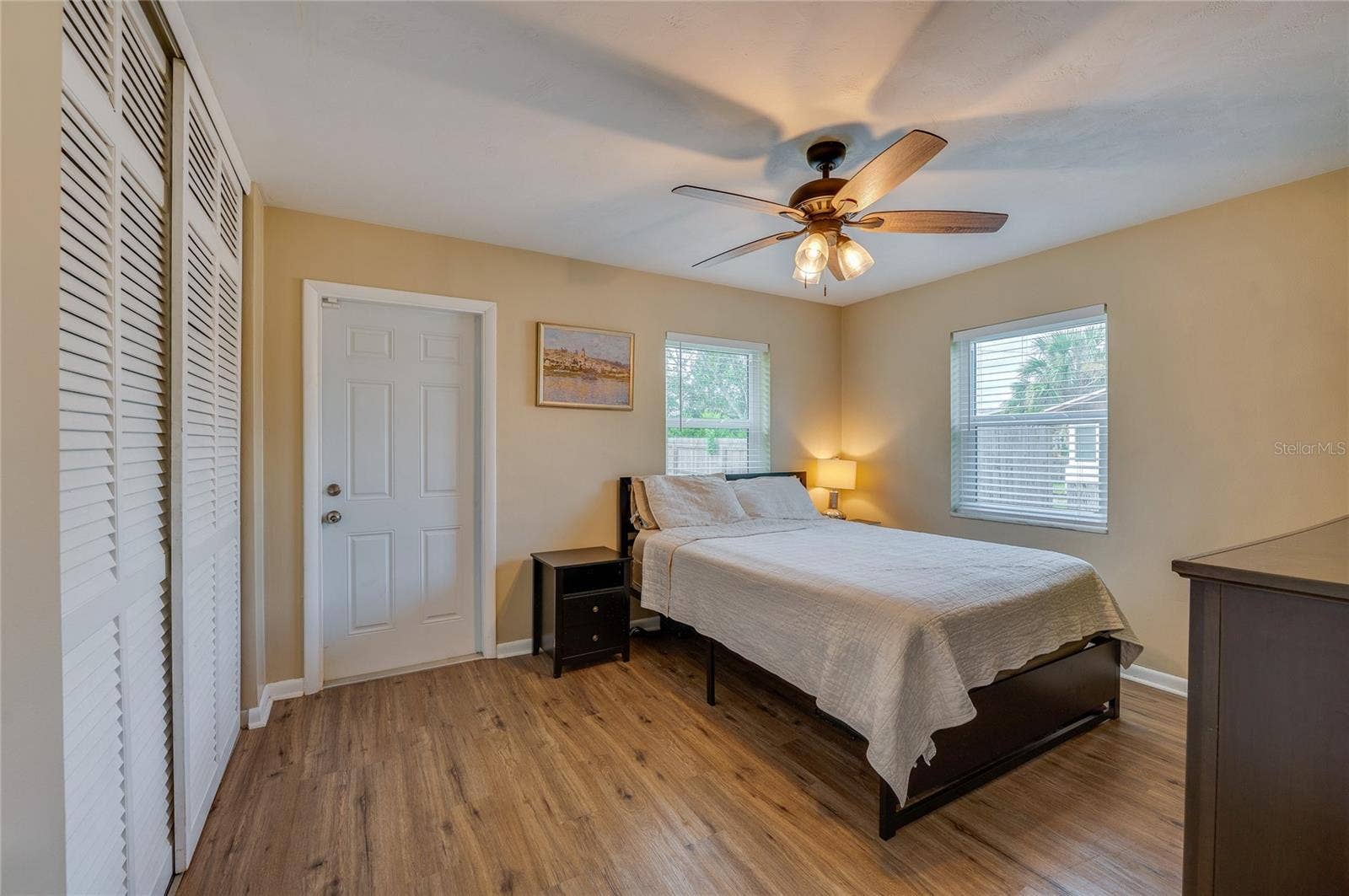 605 E NORMANDY BOULEVARD, Deltona, FL 32725 Cozy bedroom offering LVP flooring, louvered closet doors, neutral walls, and a ceiling fan with integrated lighting.