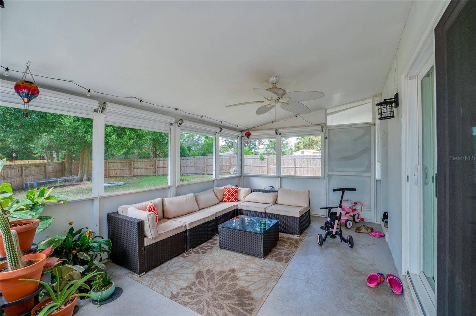 605 E NORMANDY BOULEVARD, Deltona, FL 32725 Enclosed, screened-in porch with ceiling fans and surrounding mesh screens overlooking the fenced backyard area.