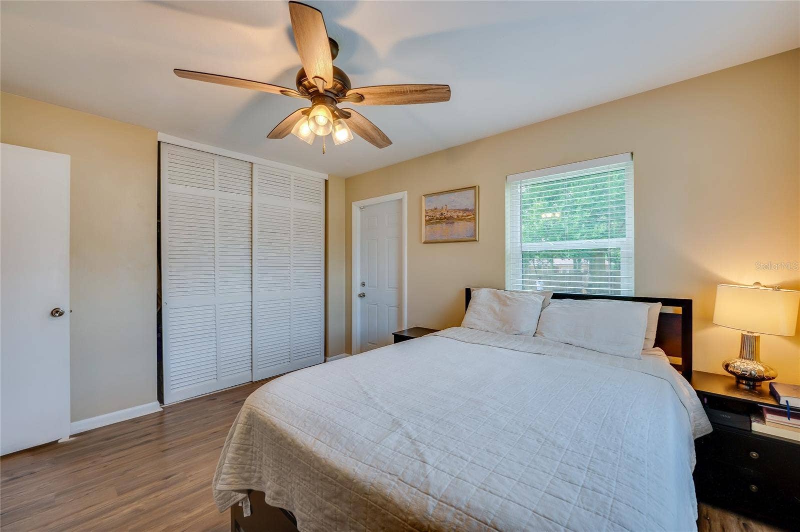 605 E NORMANDY BOULEVARD, Deltona, FL 32725 Spacious bedroom featuring warm LVP flooring, white louvered sliding closet doors, and multiple windows allowing plenty of natural light.