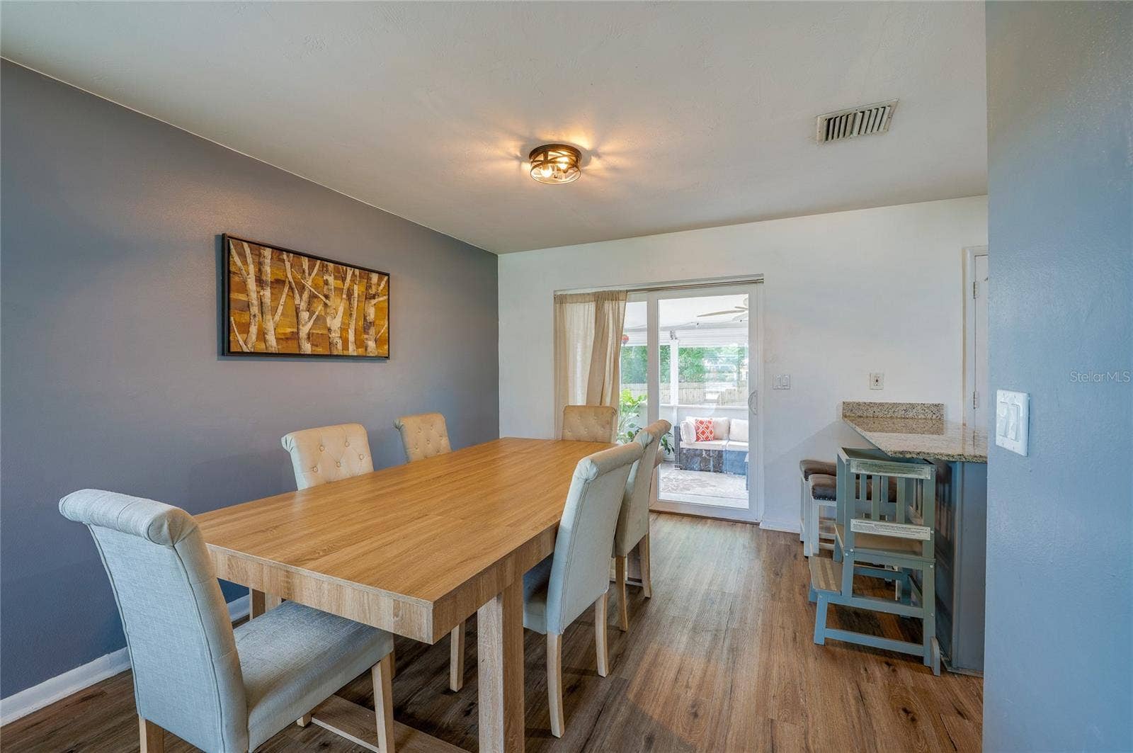 605 E NORMANDY BOULEVARD, Deltona, FL 32725 Light-filled dining area featuring LVP flooring, accent wall paint, and sliding glass doors that lead directly out to a covered patio space.