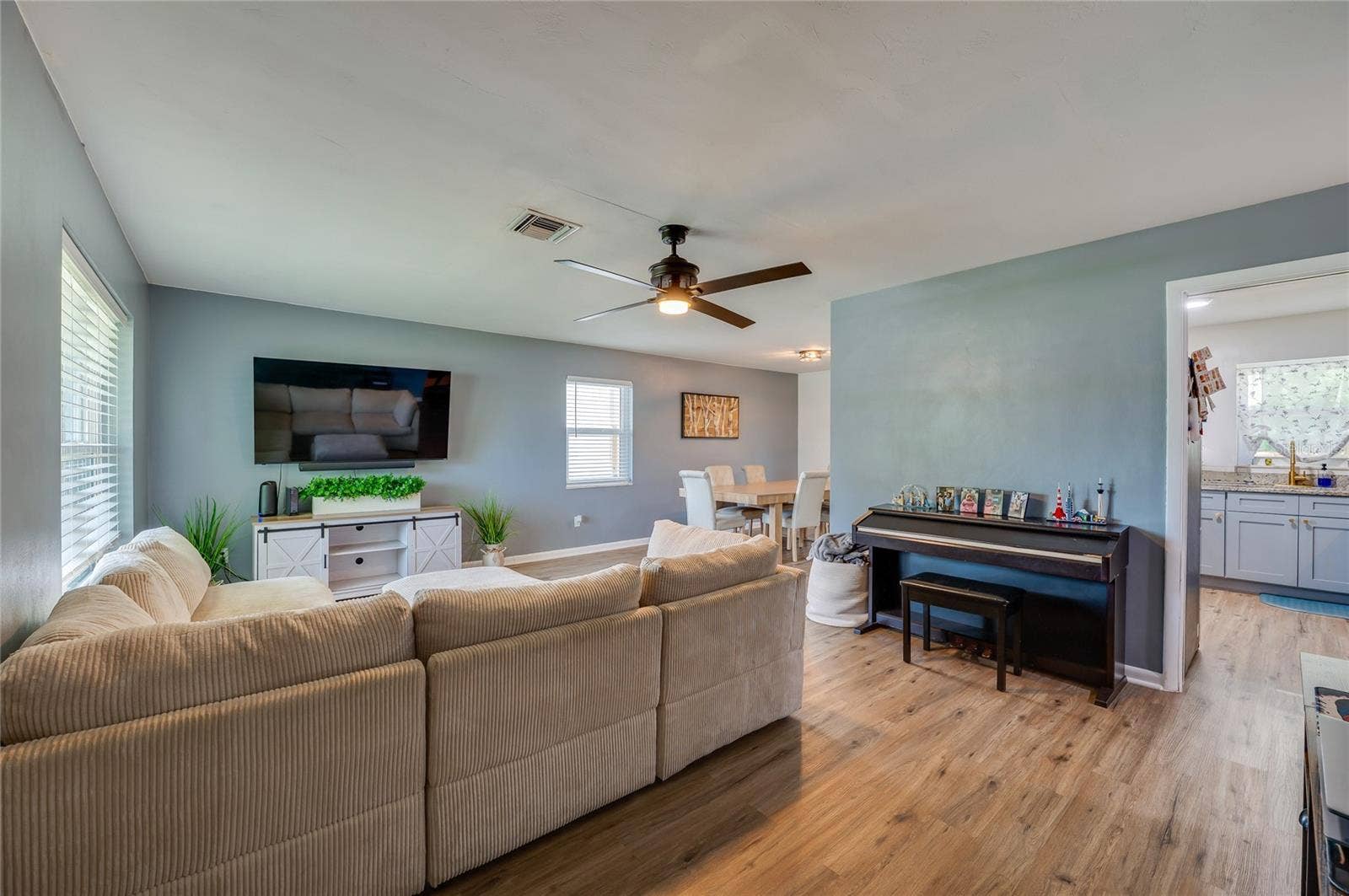 605 E NORMANDY BOULEVARD, Deltona, FL 32725 Expansive open-concept living space with LVP flooring, ceiling fans, and seamless flow into adjoining dining and kitchen areas.