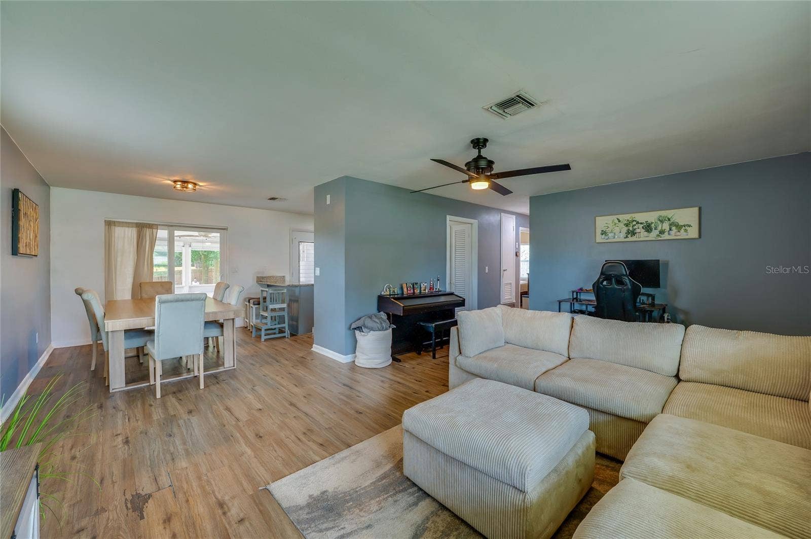 605 E NORMANDY BOULEVARD, Deltona, FL 32725 Broad view of an open layout emphasizing natural LVP floors, a ceiling fan, and clear sightlines between living and dining spaces.