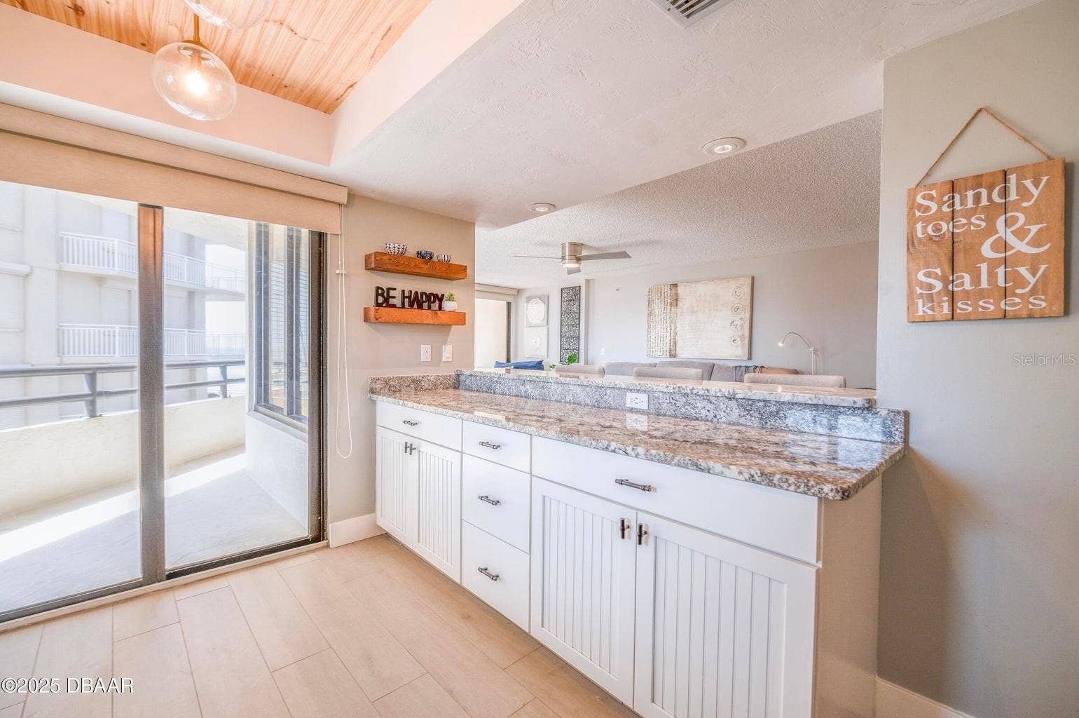 An extended granite breakfast bar provides additional seating and serving space, while ample lower cabinetry offers convenient storage. Sliding glass doors bring natural light into this open and inviting area.