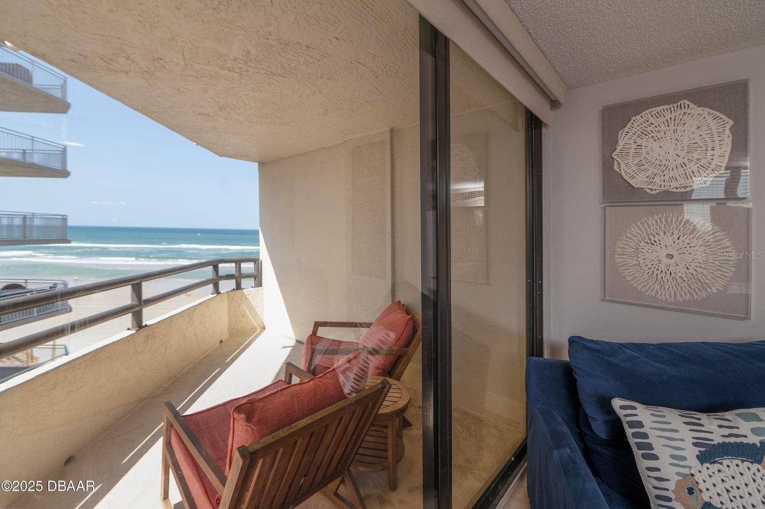 Floor-to-ceiling sliding glass doors connect the living room to the covered oceanfront balcony, offering an effortless transition between indoor comfort and outdoor relaxation.