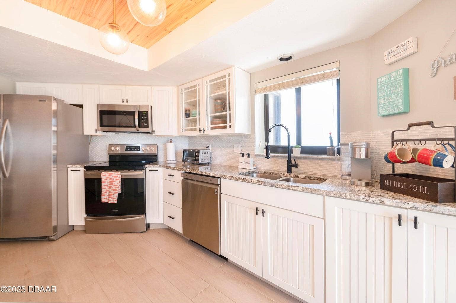 This thoughtfully designed kitchen showcases stainless steel appliances, generous counter space, white cabinetry with contrasting hardware, and a double-basin sink with a modern black faucet.