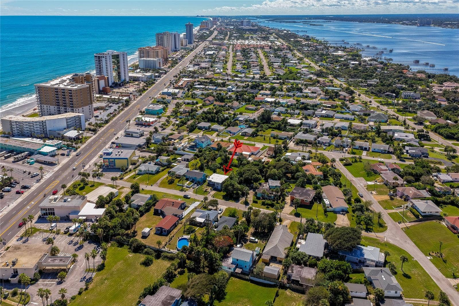 Panoramic aerial view capturing the property set between the ocean shoreline and the intracoastal waterway. The elevated perspective highlights the surrounding residential layout and scenic coastal landscape.