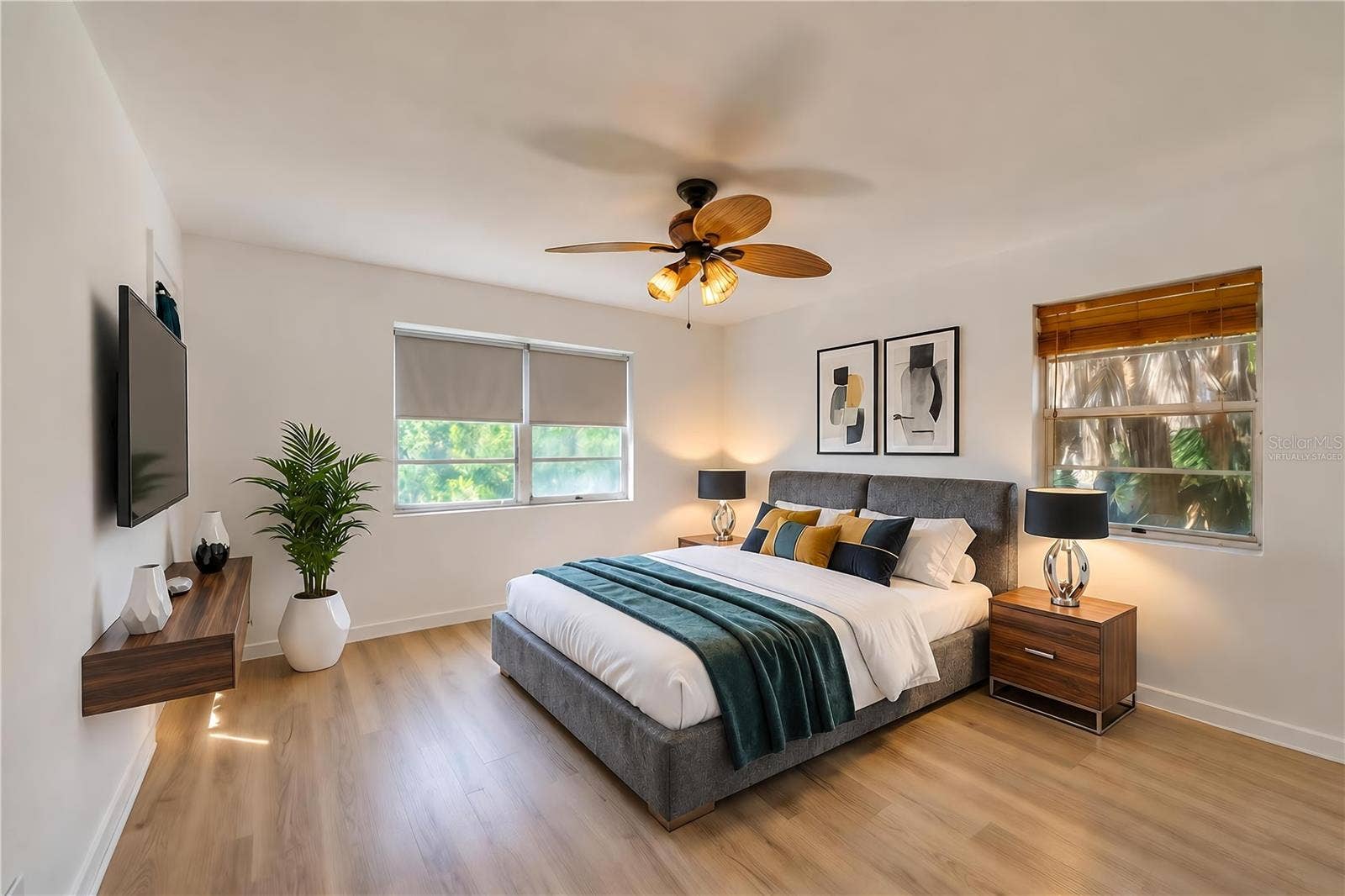 Virtually Staged - Generous interior room featuring light LVP flooring, crisp white walls, and a woven palm leaf ceiling fan. Multiple windows fill the space with natural light.