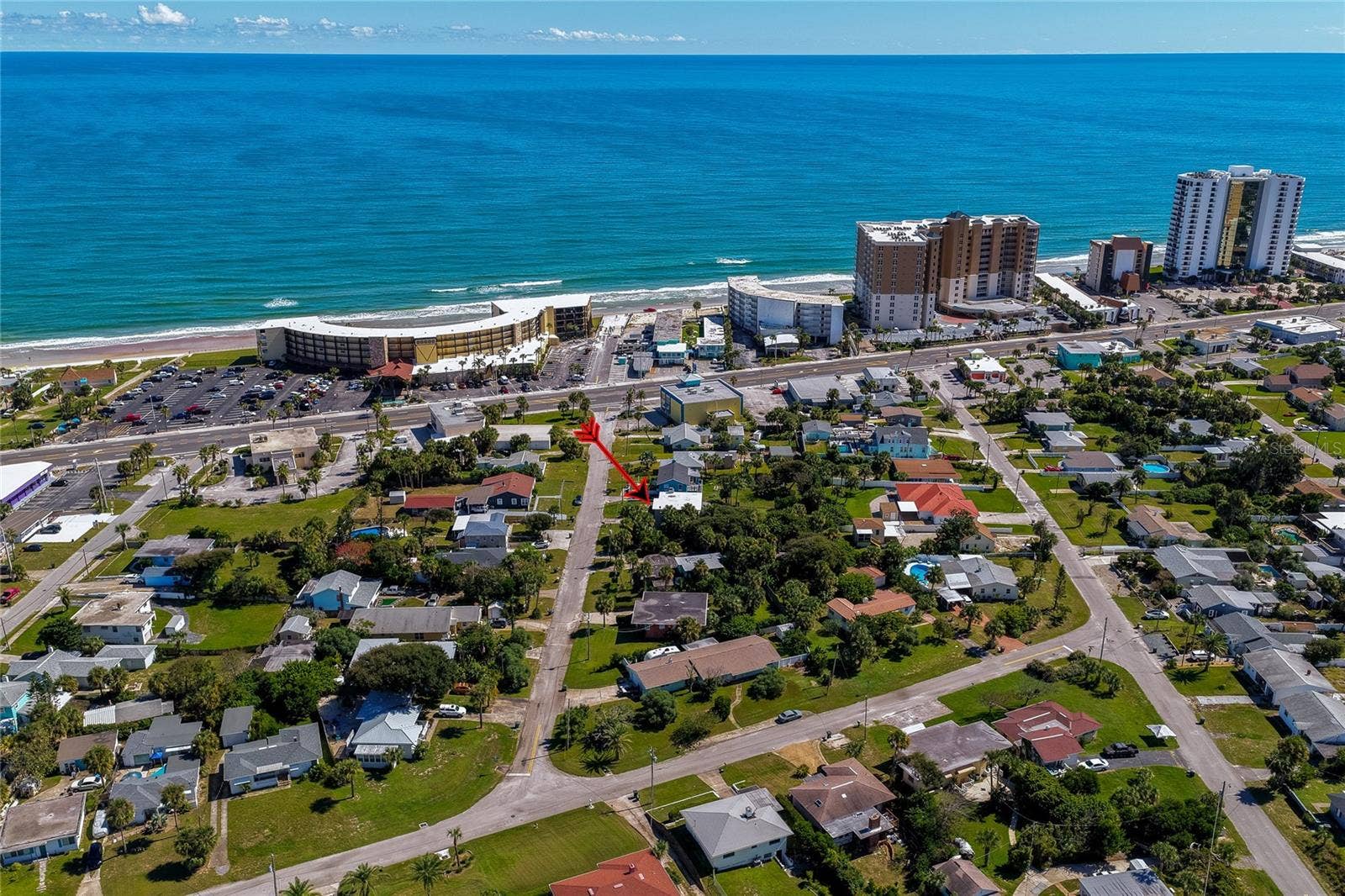 High-angle aerial shot highlighting the home's proximity to the Atlantic oceanfront and beach access corridors. Nearby high-rise resorts and coastal thoroughfares accentuate the prime location.