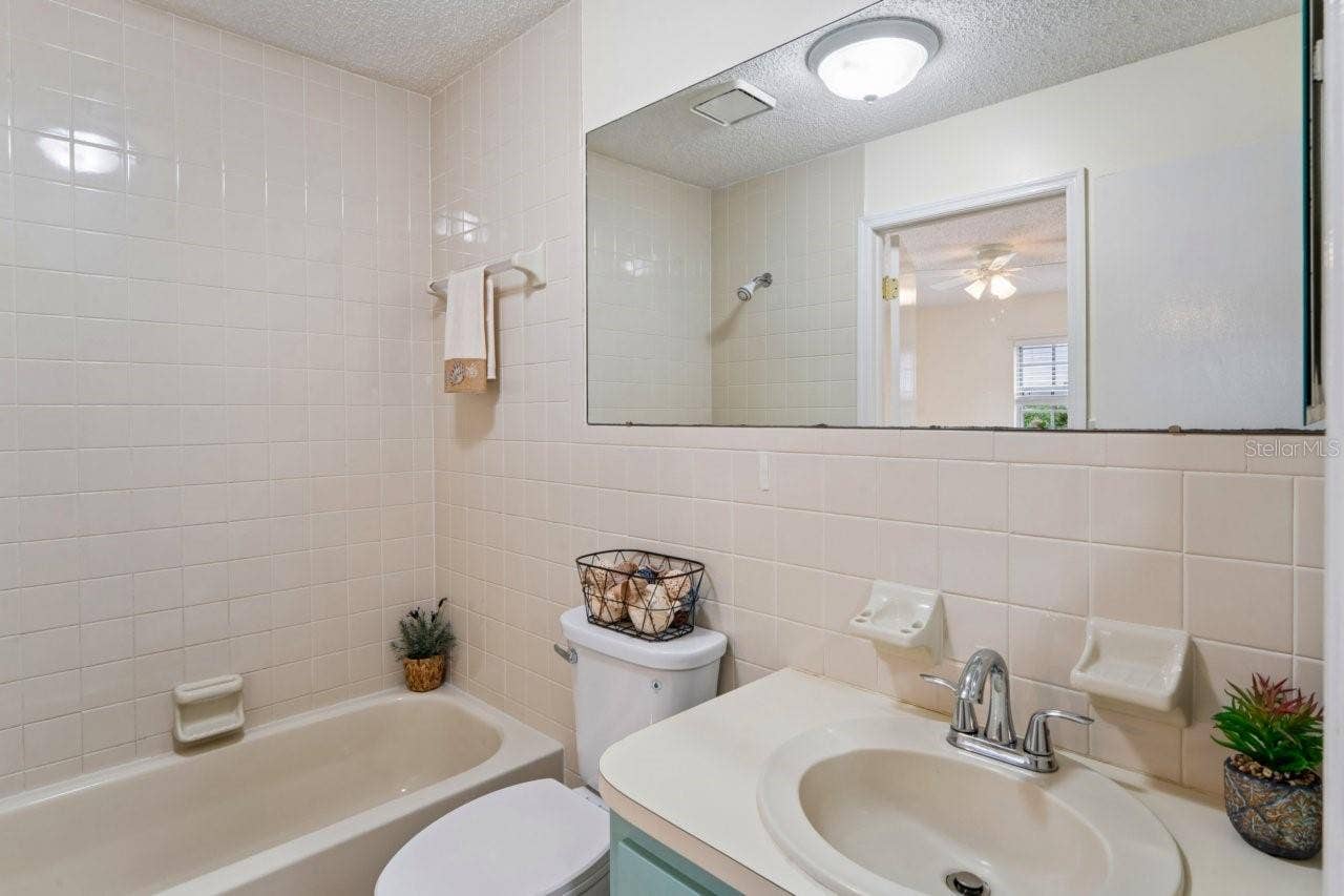 The bathroom features a tub with a shower and a single vanity, with access from both the bedroom and the living room.