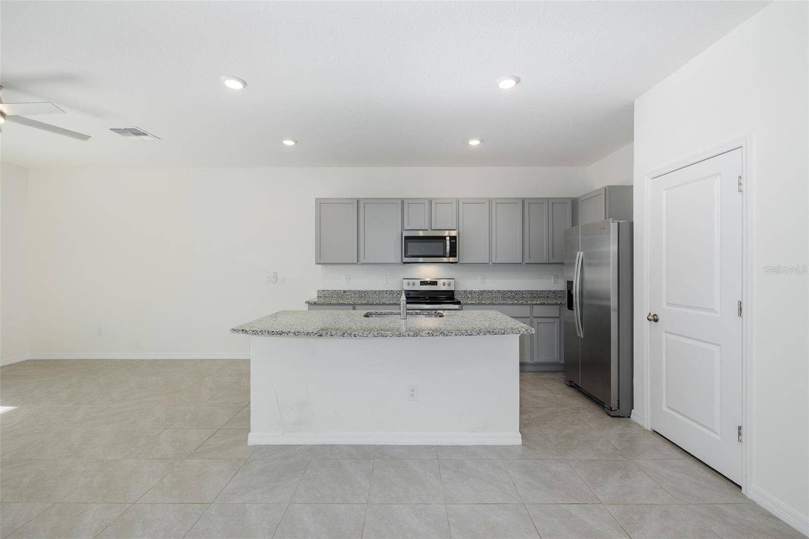 11166 CRESCENT DEER DRIVE, Land O Lakes, FL 34638 Crisp gray shaker-style cabinetry pairs beautifully with granite countertops and stainless-steel appliances for a fresh, contemporary feel