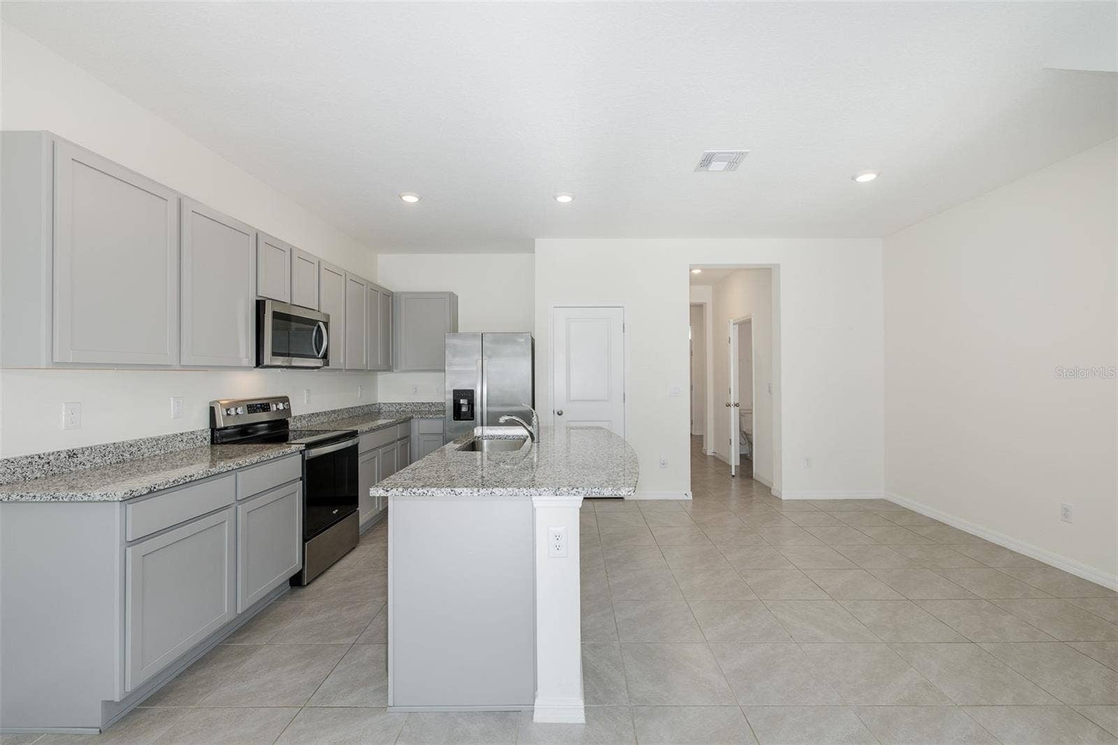 11166 CRESCENT DEER DRIVE, Land O Lakes, FL 34638 Modern, open-concept kitchen featuring granite countertops, stainless-steel appliances, gray cabinetry and a spacious center island