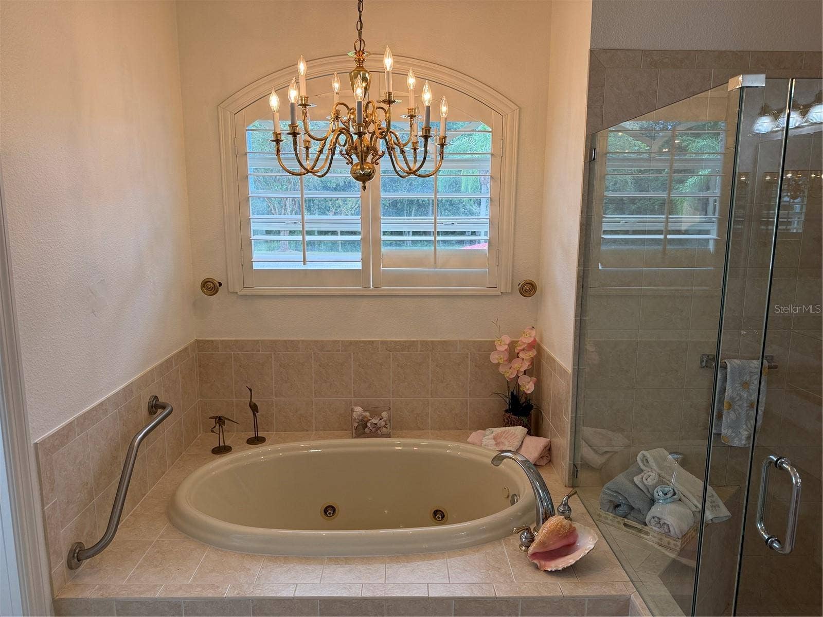 Jetted tub, chandelier, and plantation shutter in primary bathroom