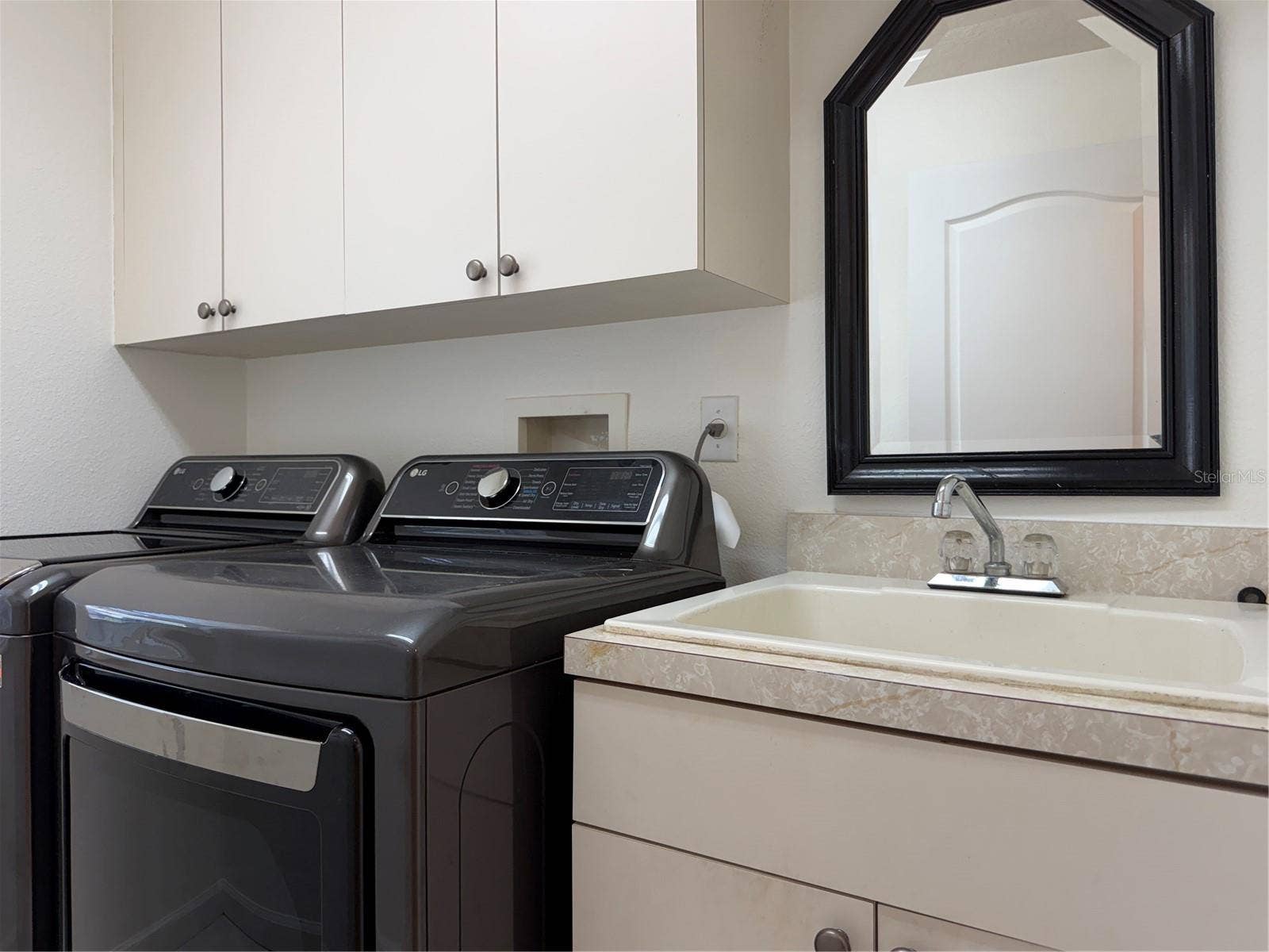 Laundry room has sink and rod for hanging clothes