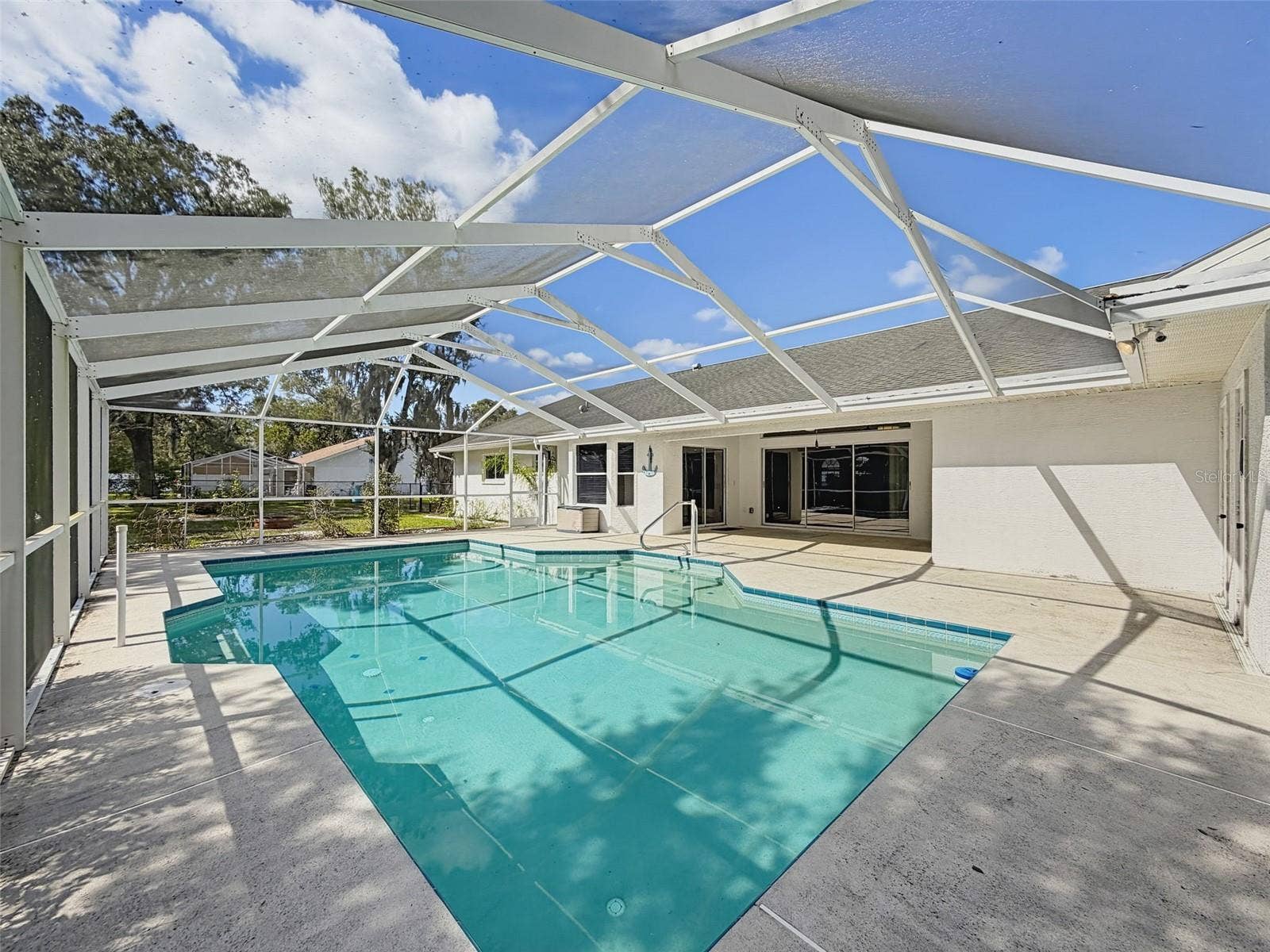 10074 SLEEPY WILLOW COURT, Spring Hill, FL 34608 Heated saltwater swimming pool with bath, outdoor shower, and storage.