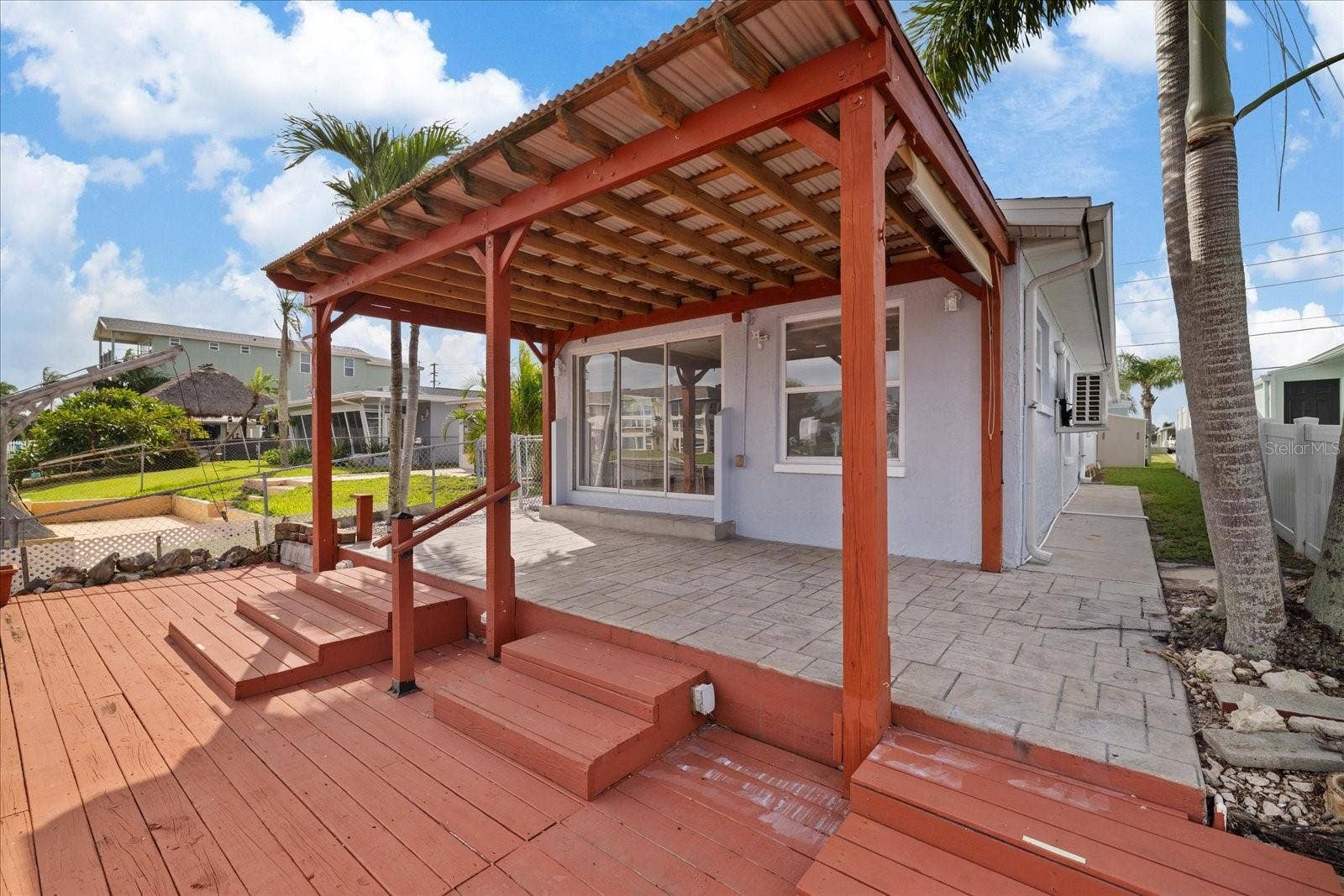 Back porch of home and view of west side yard and fence.
