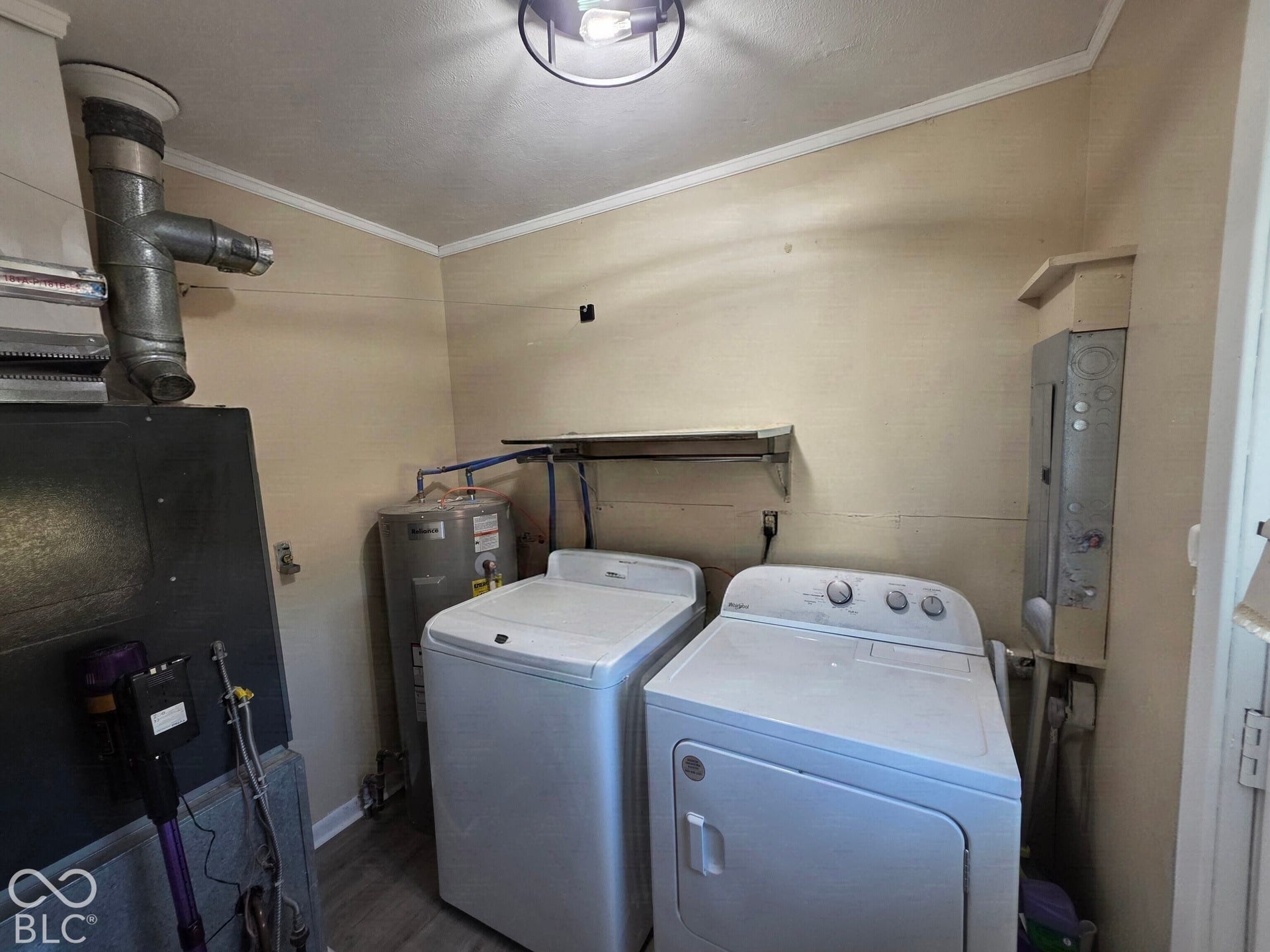 Dedicated utility room featuring wood-finish flooring, wall-mounted storage shelving, and an industrial-style overhead light fixture