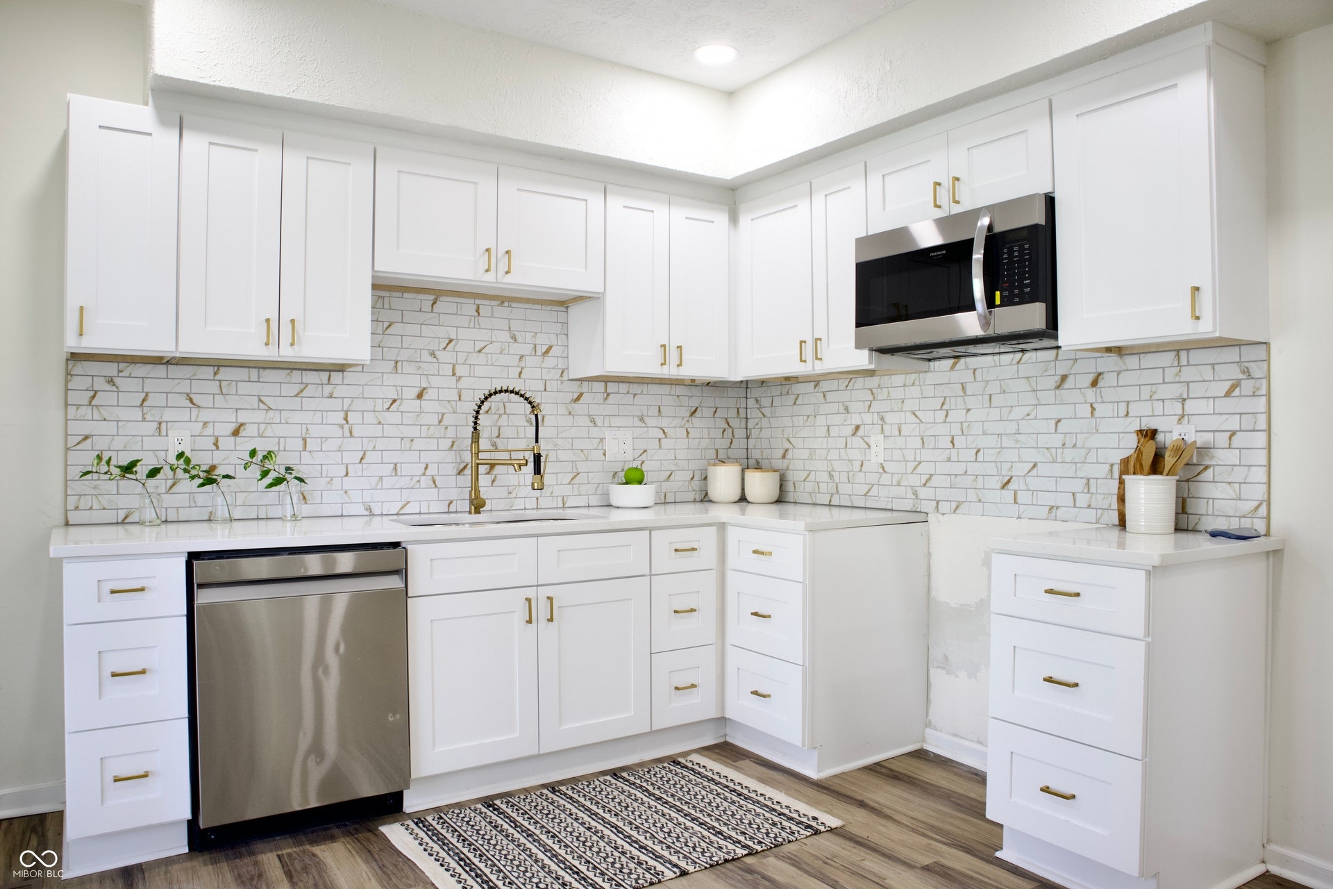 474 N Randolph Street, Indianapolis, IN 46201 Updated kitchen with white shaker cabinets, a stainless dishwasher and microwave, and gold fixtures.
