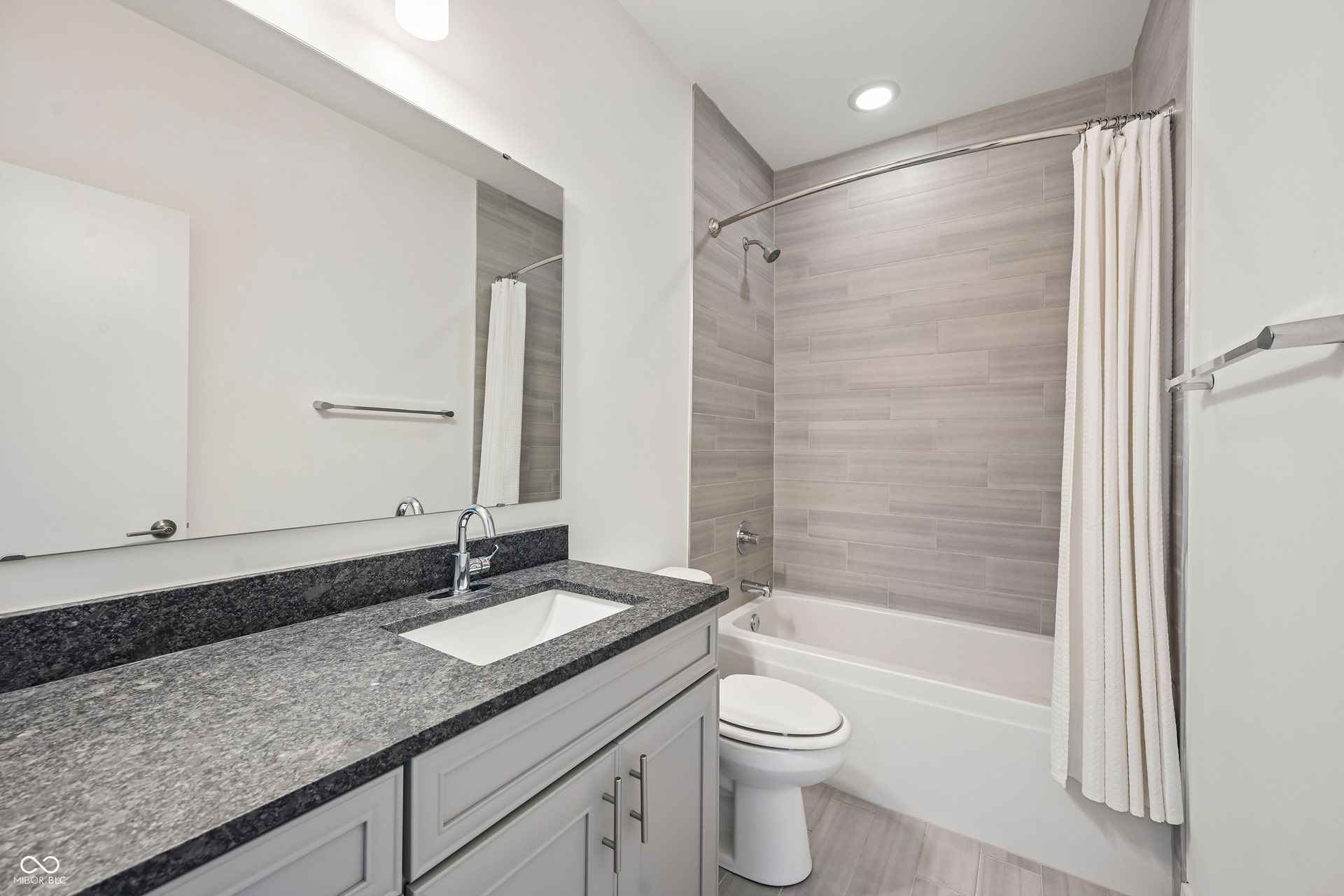 Bathroom featuring a light gray vanity with brushed nickel hardware, a dark speckled countertop, and an undermount sink
