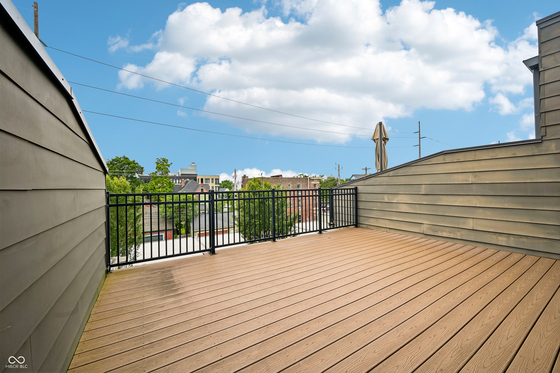 Expansive rooftop deck featuring composite wood-finish flooring and black metal railings