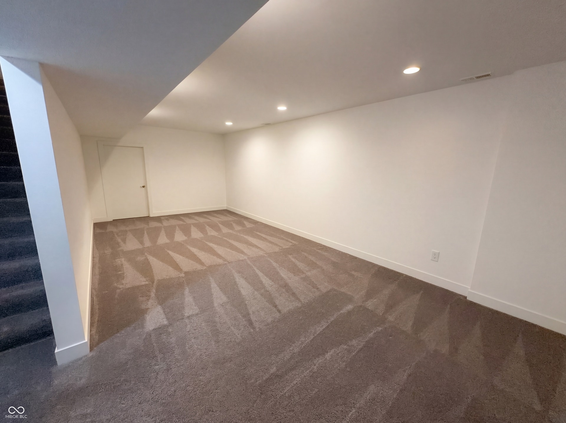 Spacious interior room with light-toned walls and recessed ceiling lighting