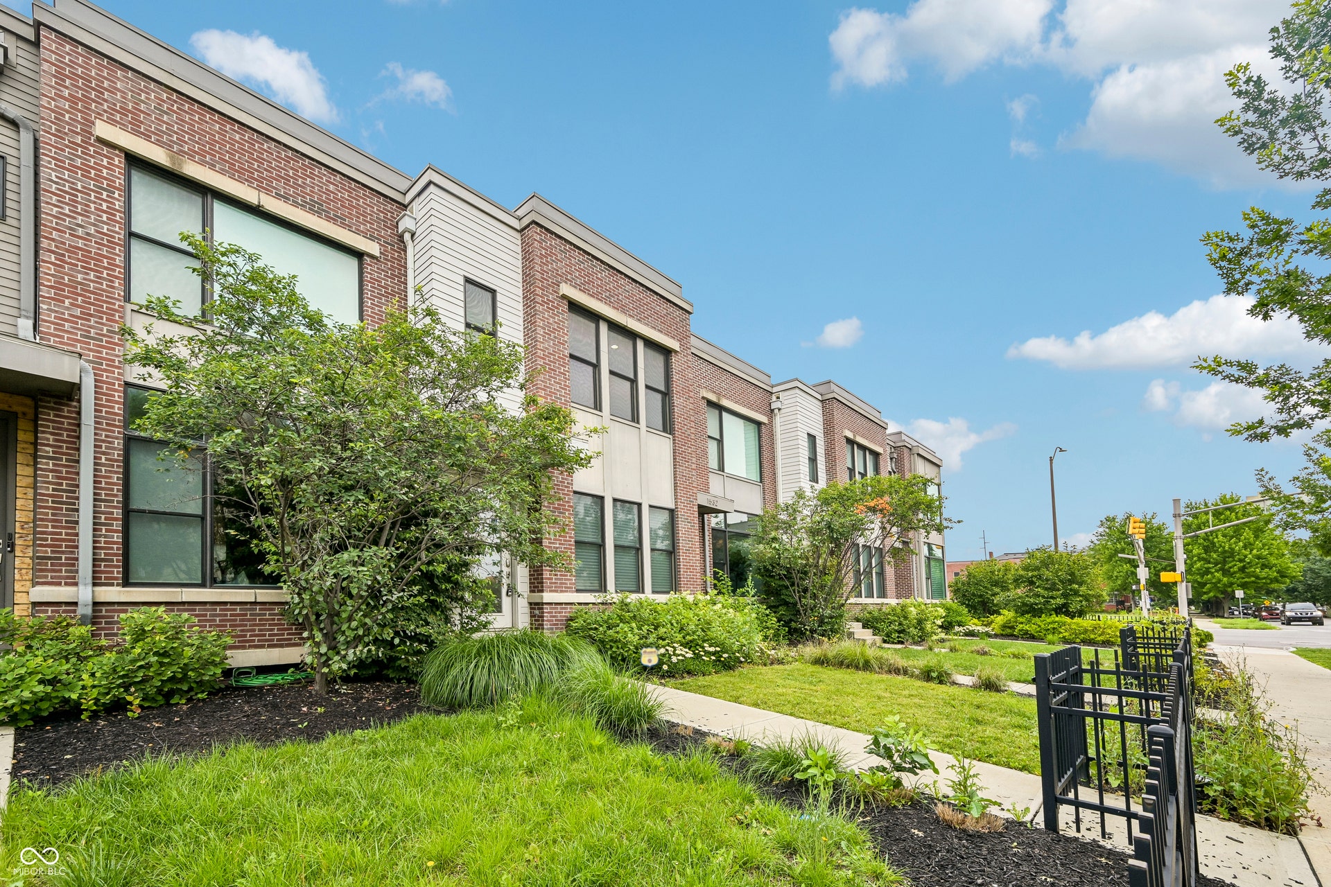 Contemporary townhome with a brick and siding facade, featuring large windows and a manicured front yard