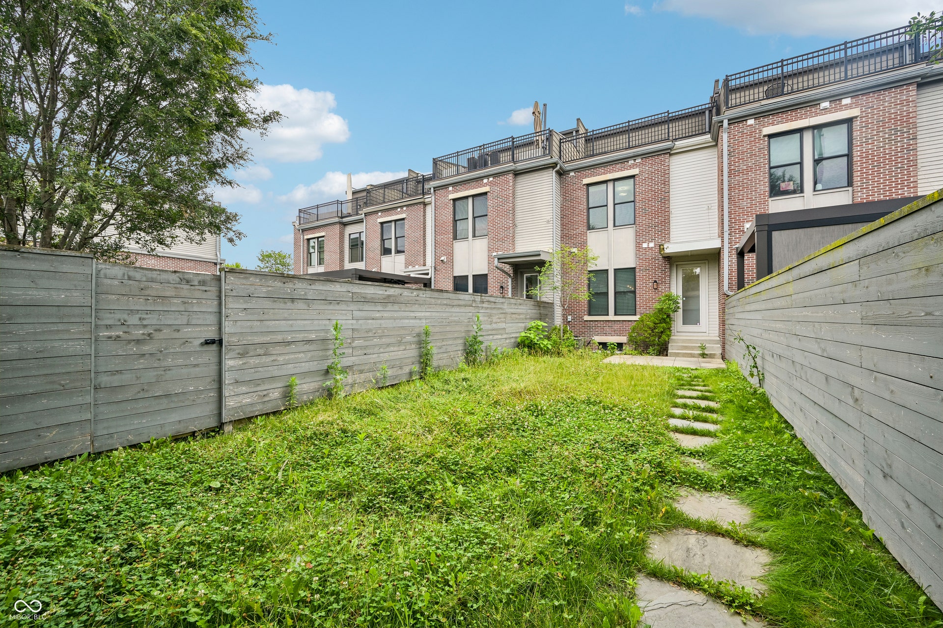 Private fenced backyard featuring a stone stepping-stone path leading to a rear entry door