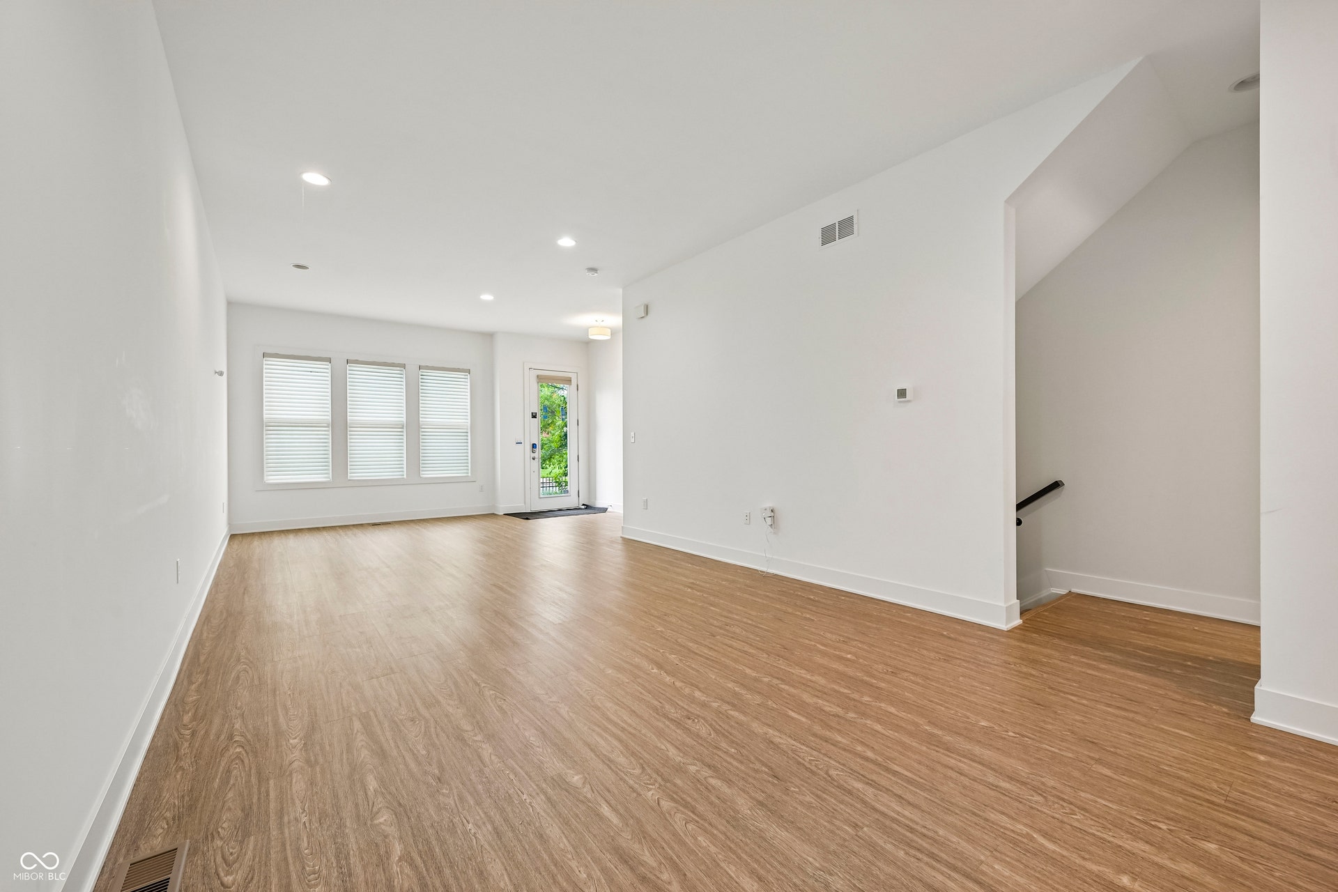 Spacious living area featuring wood-finish flooring, recessed lighting, and white baseboards