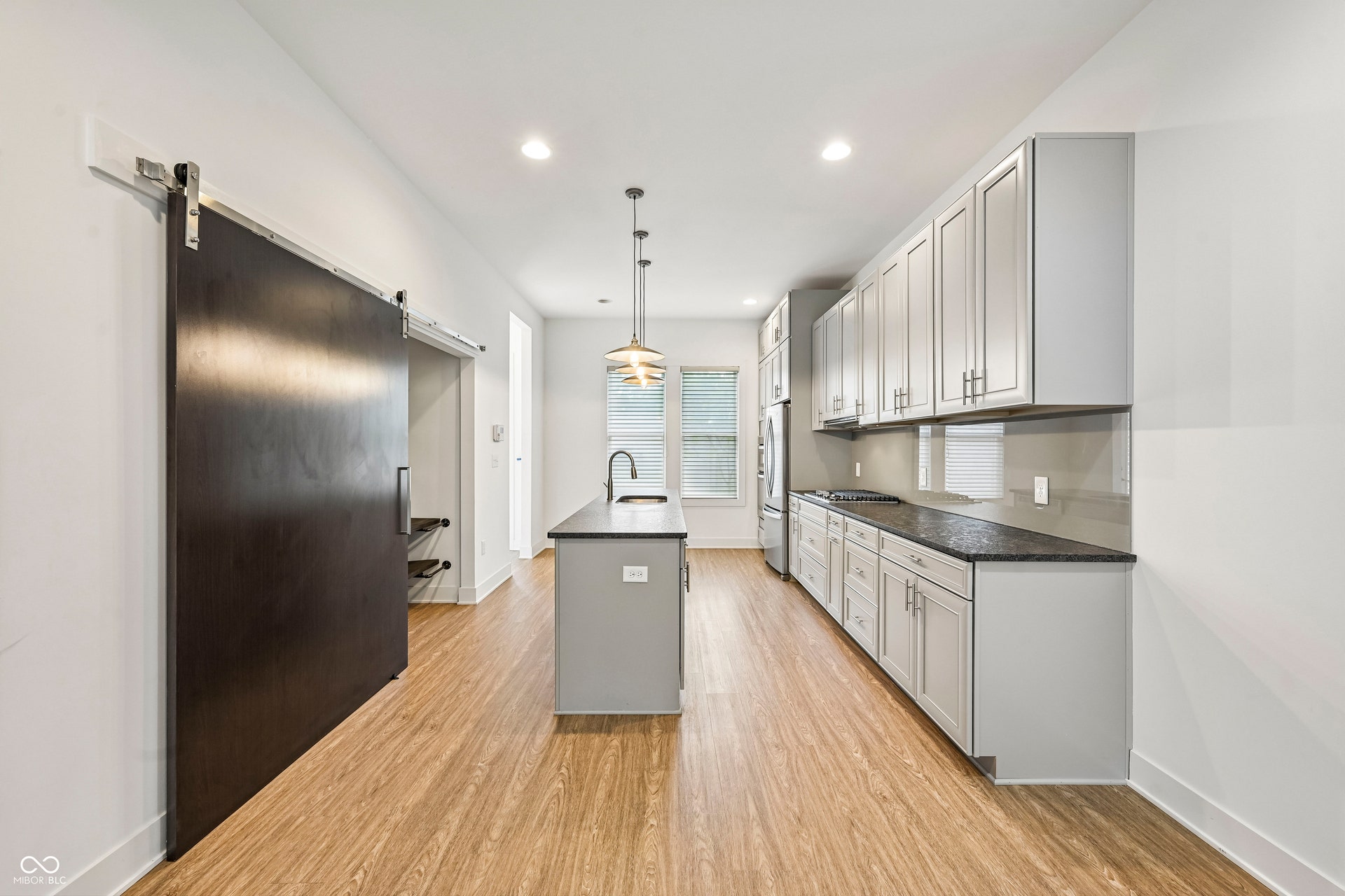 Contemporary kitchen featuring an island with an undermount sink and pendant lighting