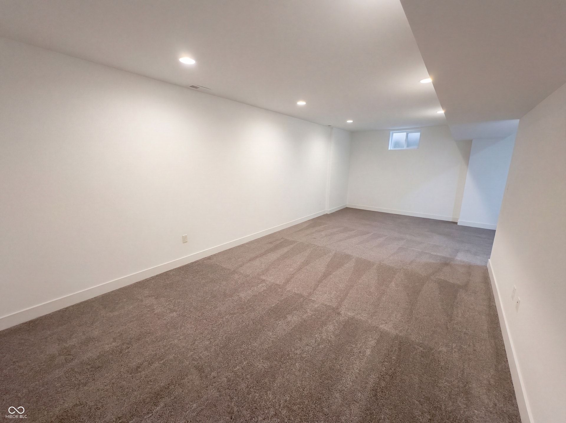 Spacious room featuring neutral carpet flooring, recessed lighting, white walls, white trim, and a high-set window