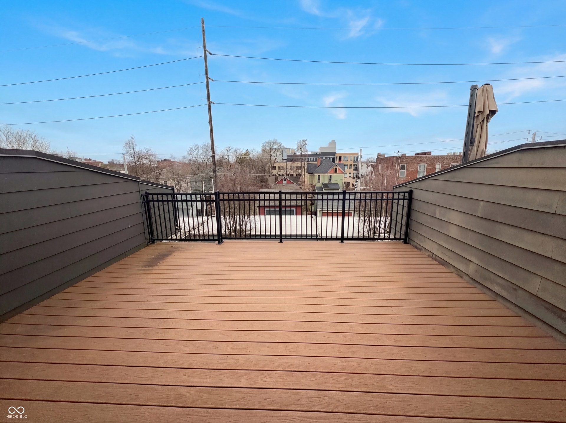 Rooftop deck featuring composite wood-finish decking, black metal railing, and sloped exterior walls with horizontal siding