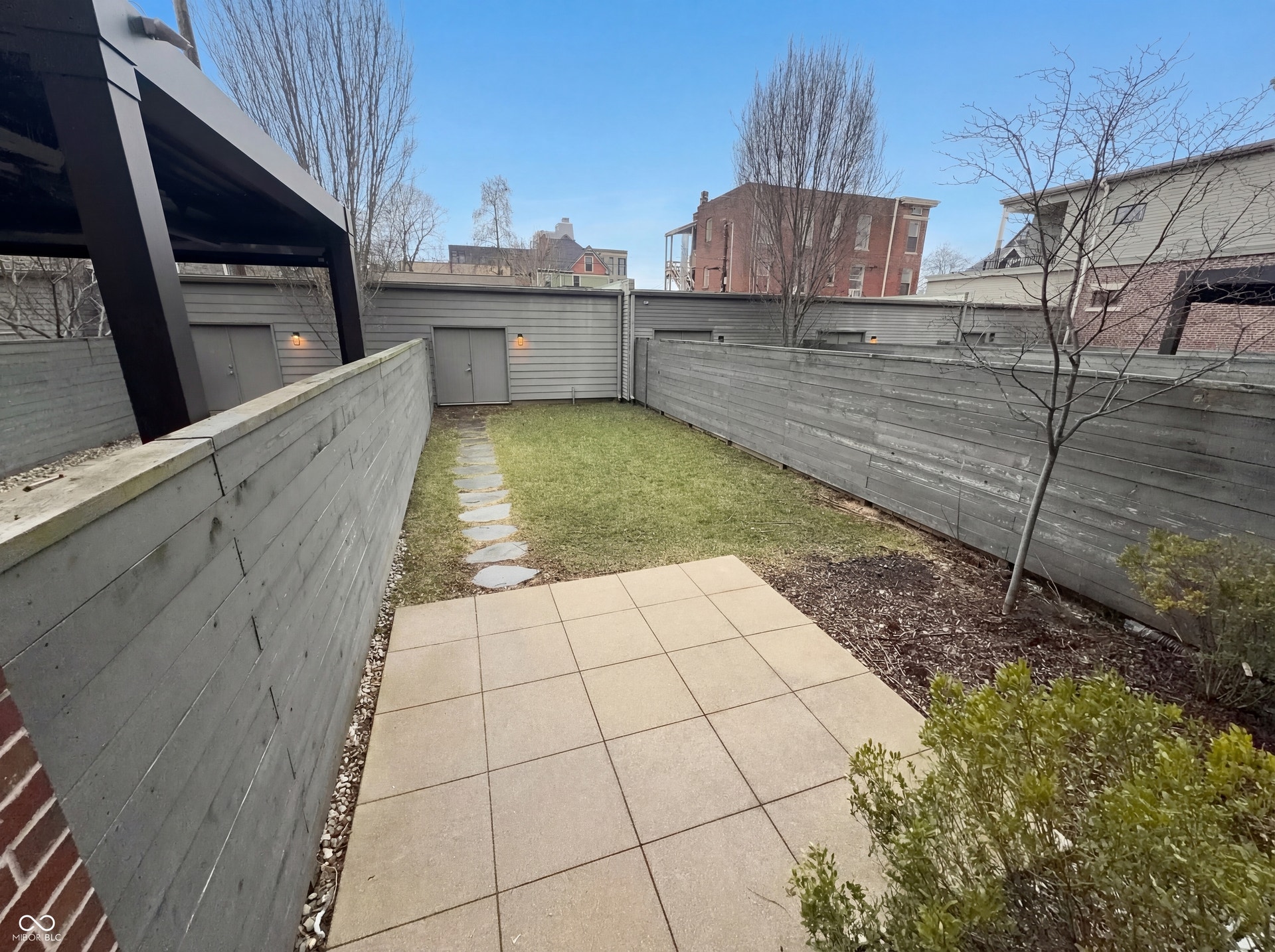 Private patio with paver flooring, leading to a landscaped lawn with stepping stones