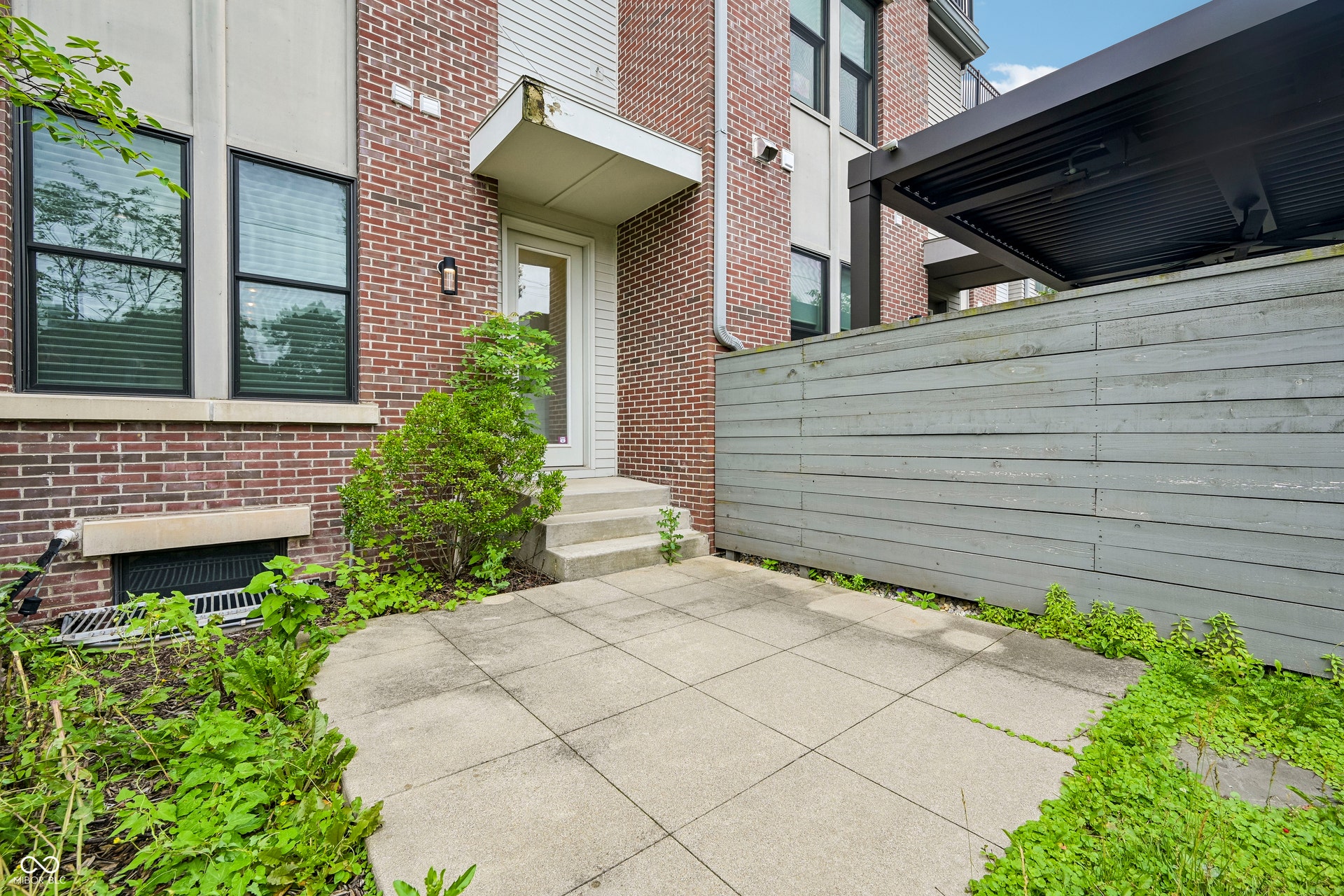 Private patio space featuring square concrete pavers, a privacy fence, and a modern pergola structure