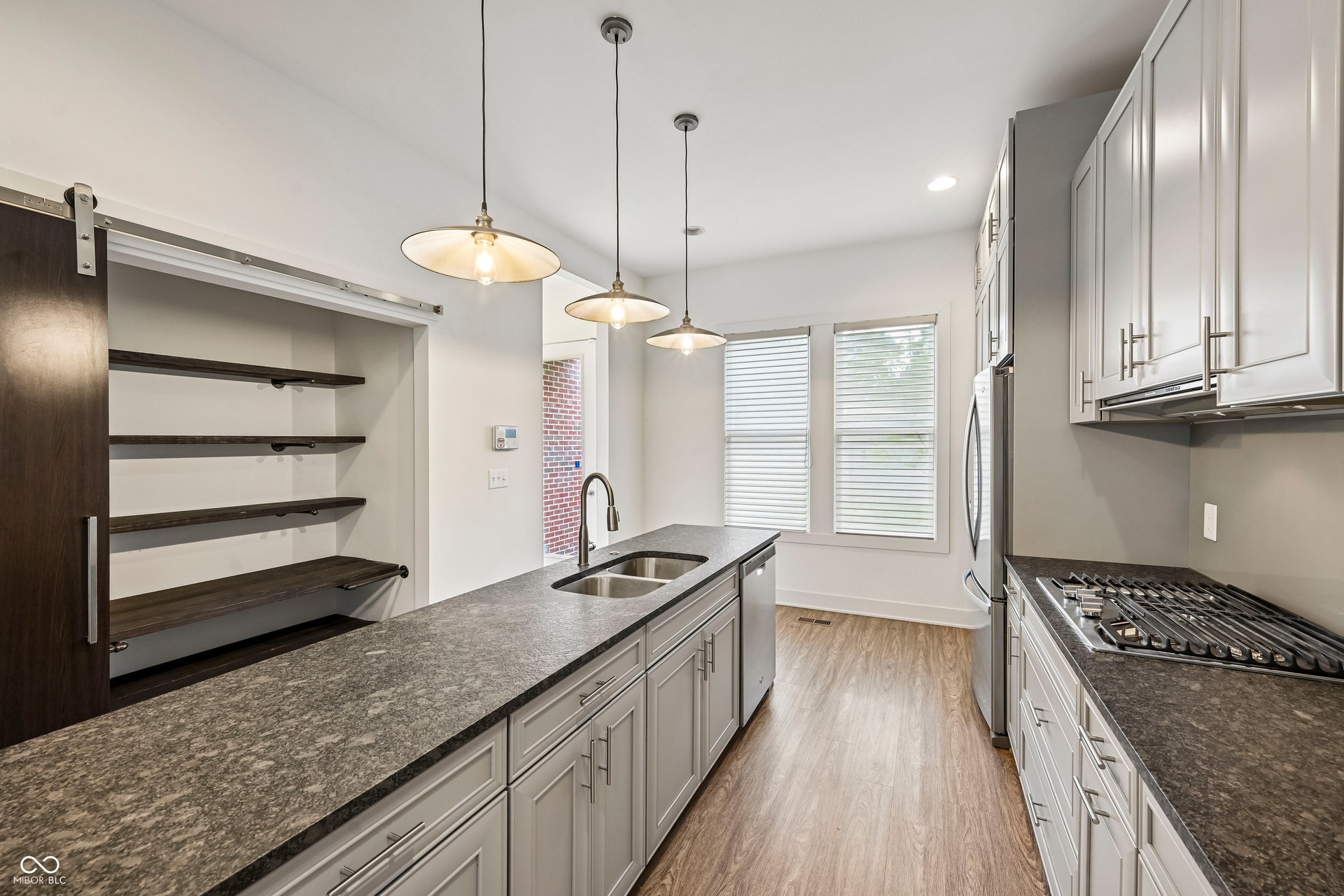 Modern kitchen featuring light grey cabinetry, dark speckled countertops, and wood-finish flooring