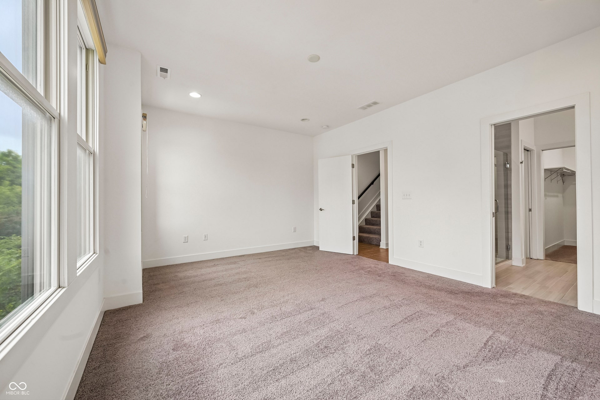 Spacious room featuring broad windows, recessed lighting, and neutral carpeting