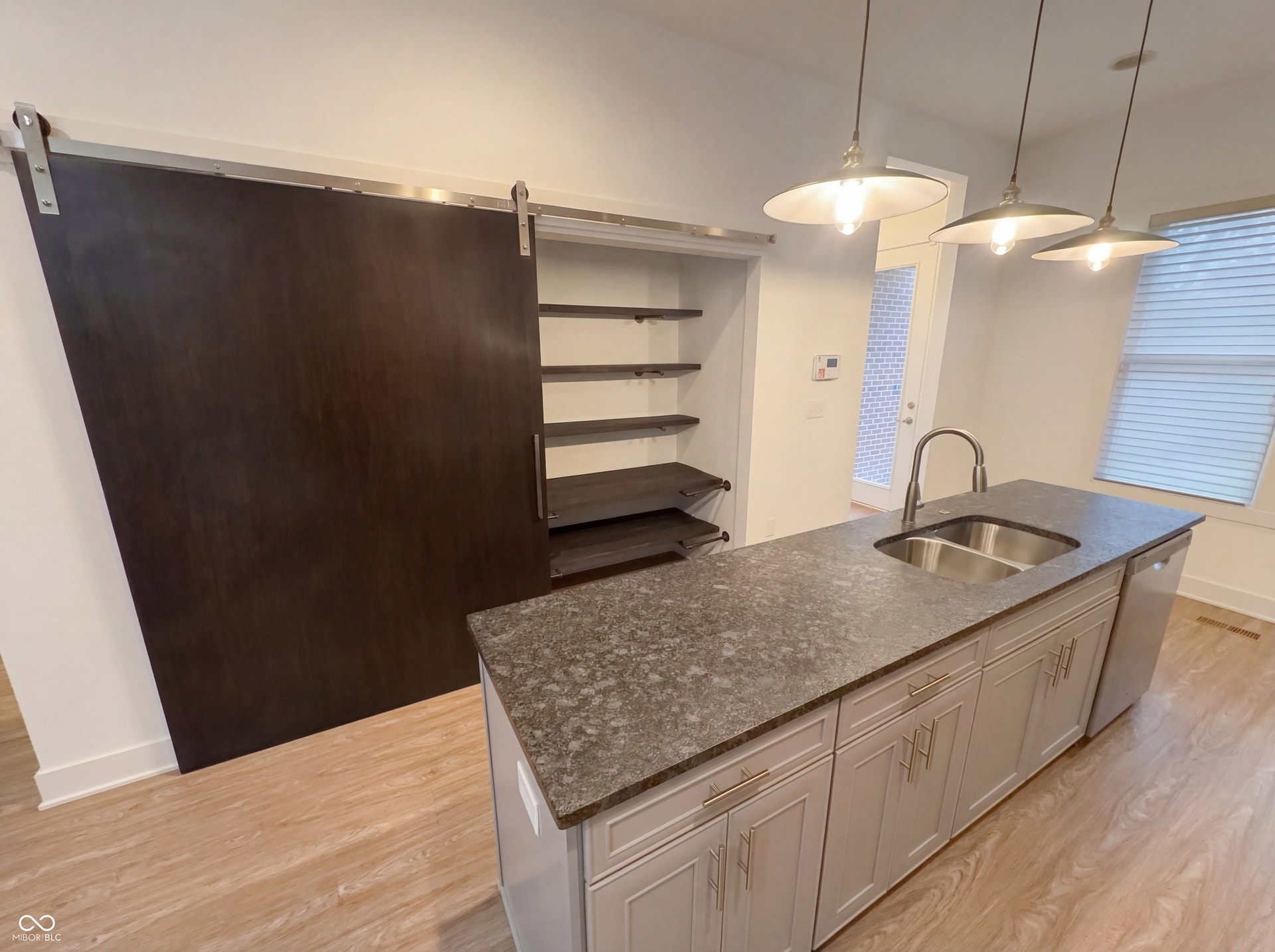 Kitchen island featuring a dual basin sink, gooseneck faucet, and integrated dishwasher