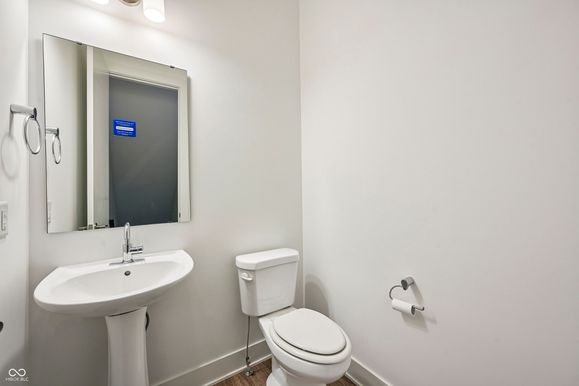 Bathroom featuring a pedestal sink with chrome faucet, a rectangular wall-mounted mirror, and a two-piece toilet