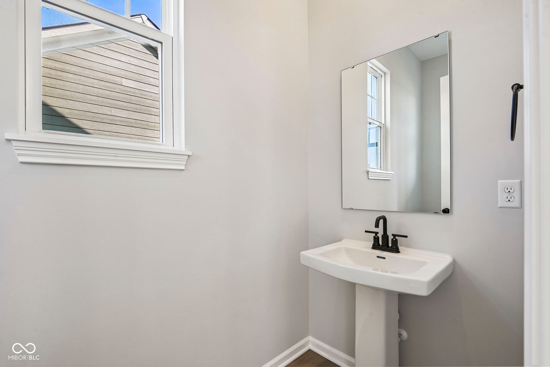 15691 Showdown Road, Noblesville, IN 46060 Pedestal sink with matte black faucet, rectangular wall-mounted mirror, and white trim window