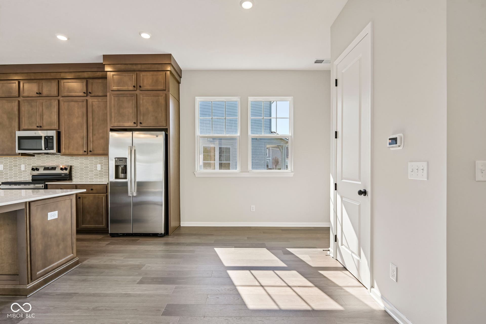 15691 Showdown Road, Noblesville, IN 46060 Kitchen featuring wood-finish cabinetry, stainless steel appliances, a tile backsplash, and a central island with a light-toned countertop
