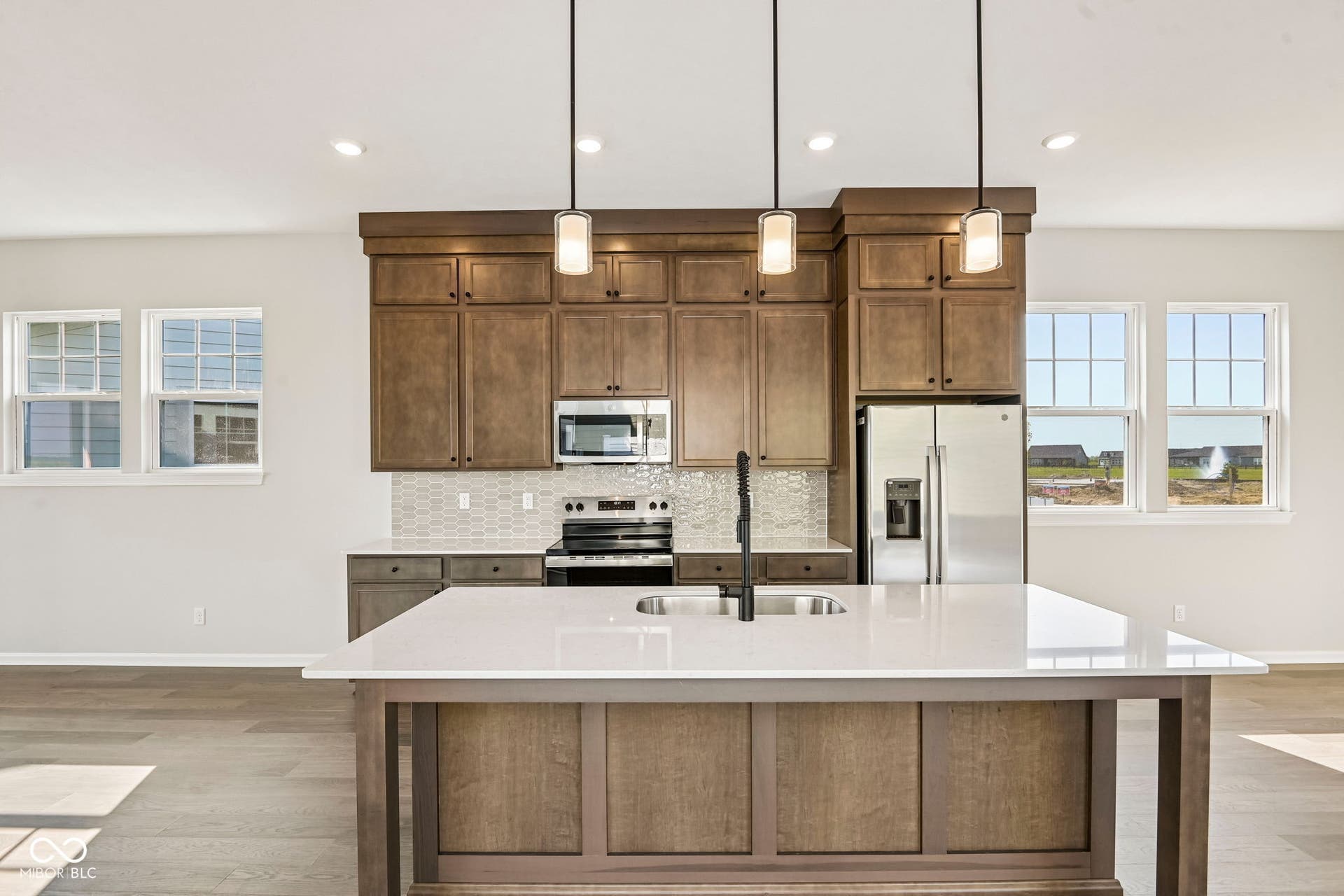 15691 Showdown Road, Noblesville, IN 46060 Kitchen island with a white solid surface countertop and undermount sink, complemented by pendant lighting