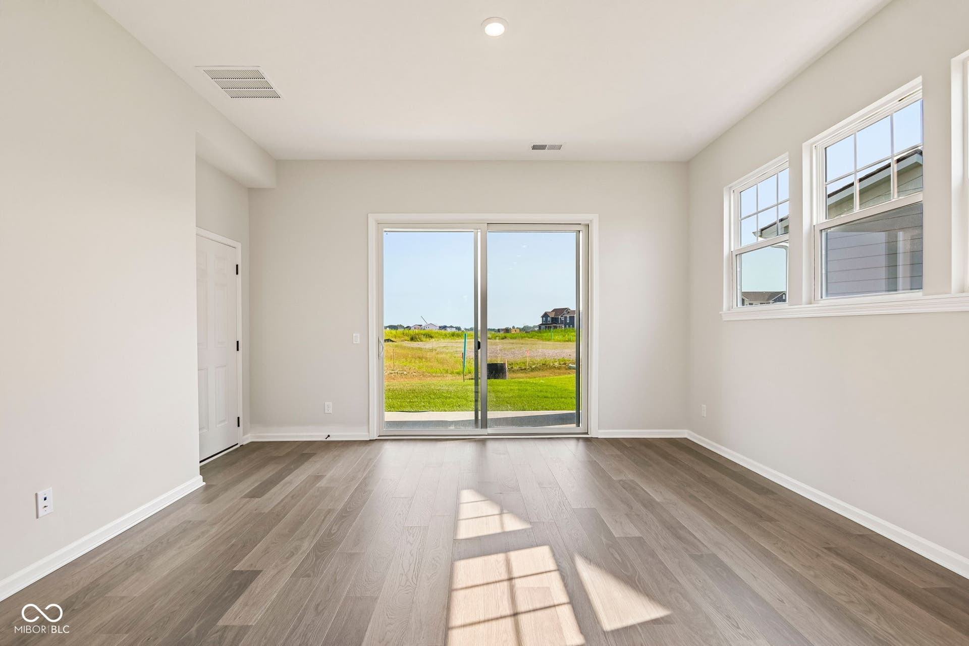 15691 Showdown Road, Noblesville, IN 46060 Spacious room featuring wood-finish flooring, light-colored walls, and a large sliding glass door opening to an outdoor patio