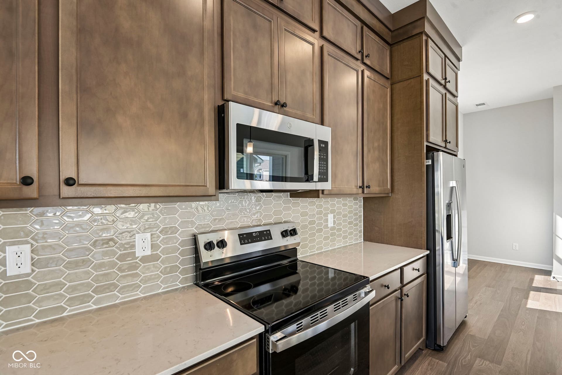 15691 Showdown Road, Noblesville, IN 46060 Modern kitchen featuring stainless steel appliances, abundant cabinetry, stone-finish countertops, geometric tile backsplash, and wood-finish flooring