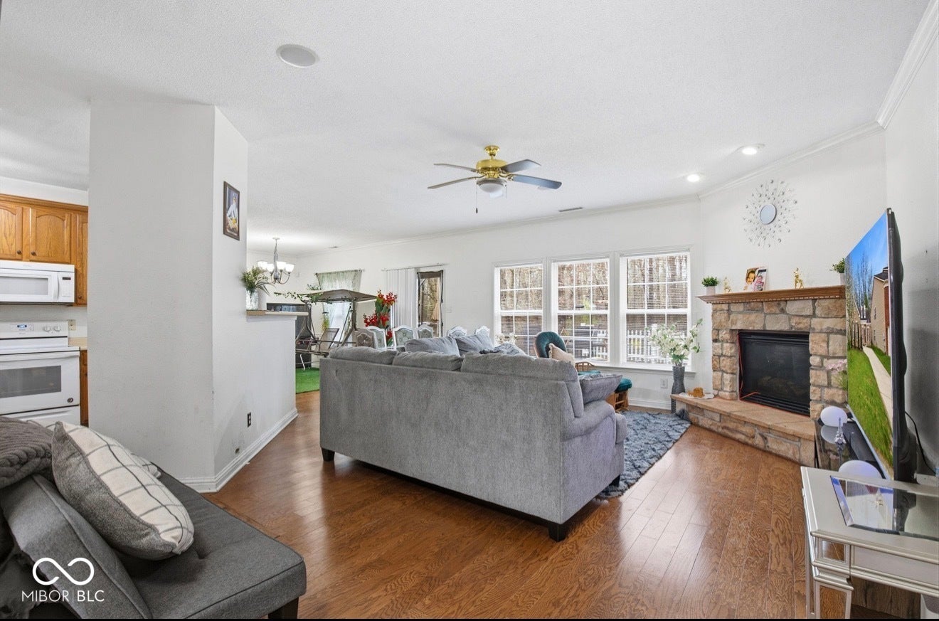 344 Legacy Boulevard, Greenwood, IN 46143 living area with ceiling fan, wood finished floors, a fireplace, crown molding, and hanging lights