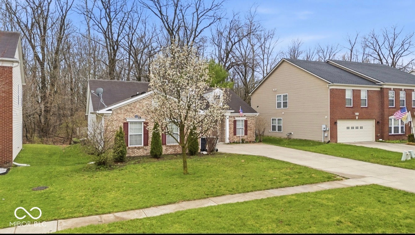 344 Legacy Boulevard, Greenwood, IN 46143 view of front of property featuring driveway, brick siding, a front yard, and a shingled roof