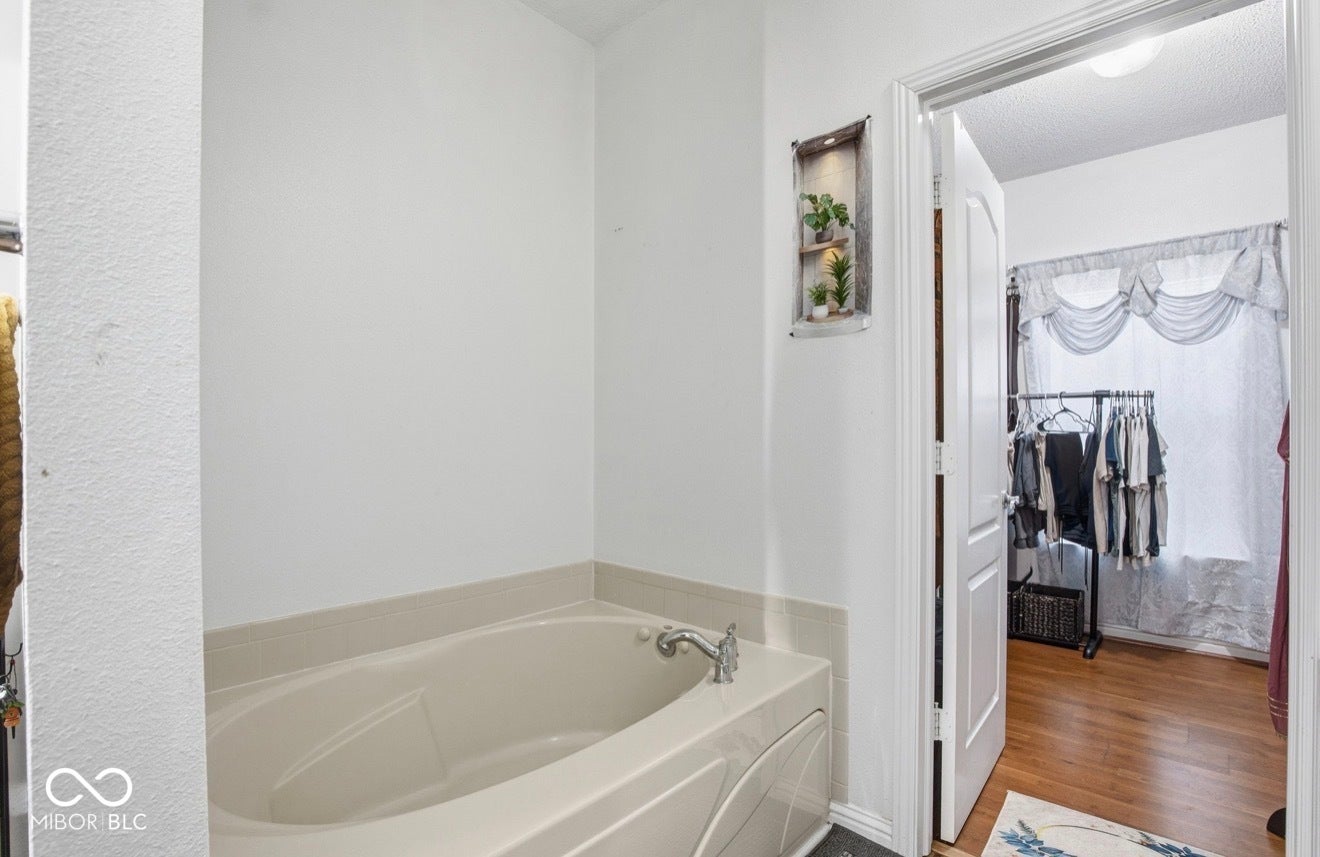 344 Legacy Boulevard, Greenwood, IN 46143 full bath featuring a garden tub, wood finished floors, and a textured ceiling