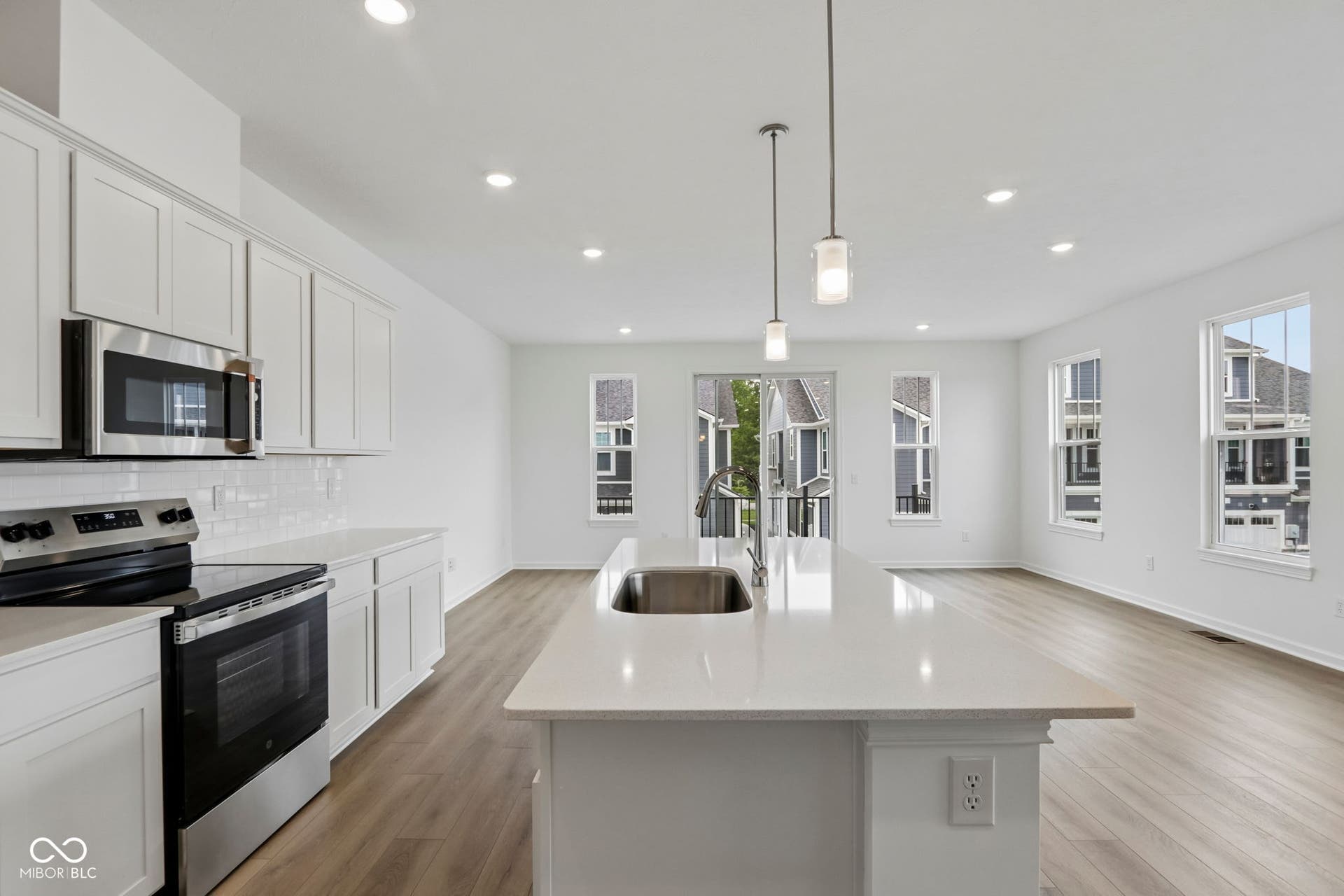 5748 Arcade Boulevard, McCordsville, IN 46055 Kitchen featuring a large island with an undermount sink, white cabinetry, stainless steel appliances, and wood-finish flooring