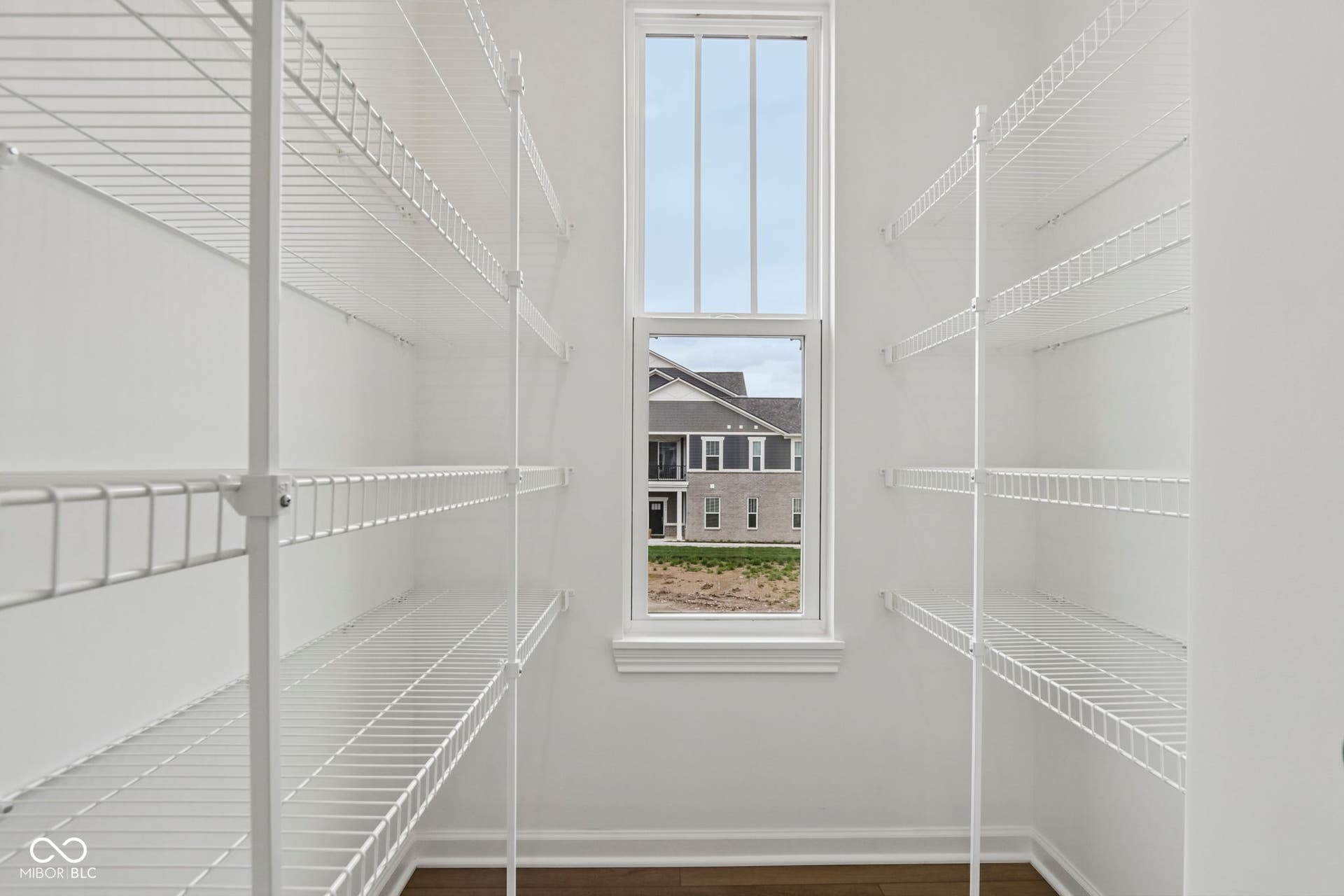 5748 Arcade Boulevard, McCordsville, IN 46055 Spacious pantry featuring extensive wire shelving, a tall window, white trim, and wood-finish flooring