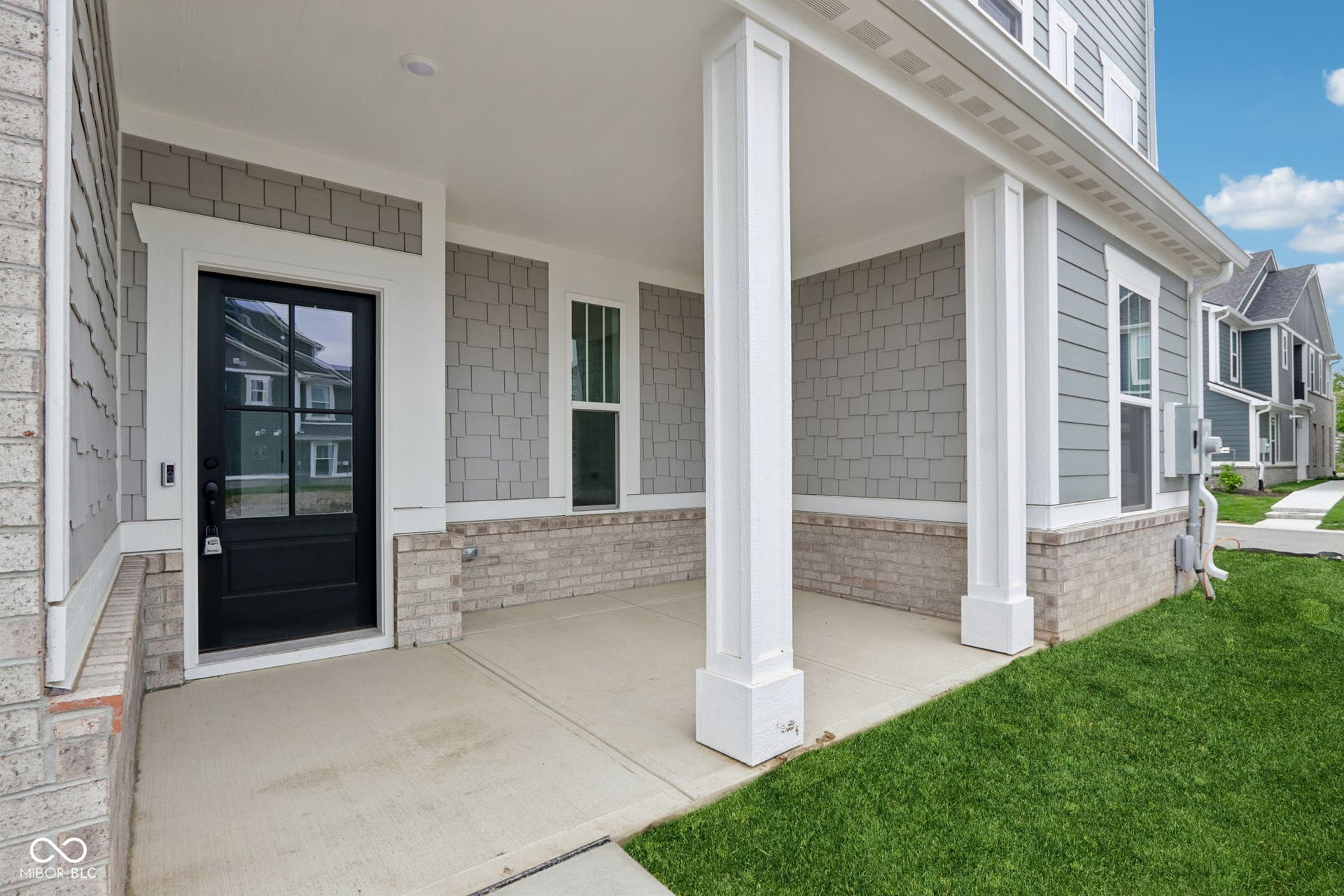 5748 Arcade Boulevard, McCordsville, IN 46055 Covered front porch featuring a dark paneled entry door with glass inserts, white trim, and a concrete slab